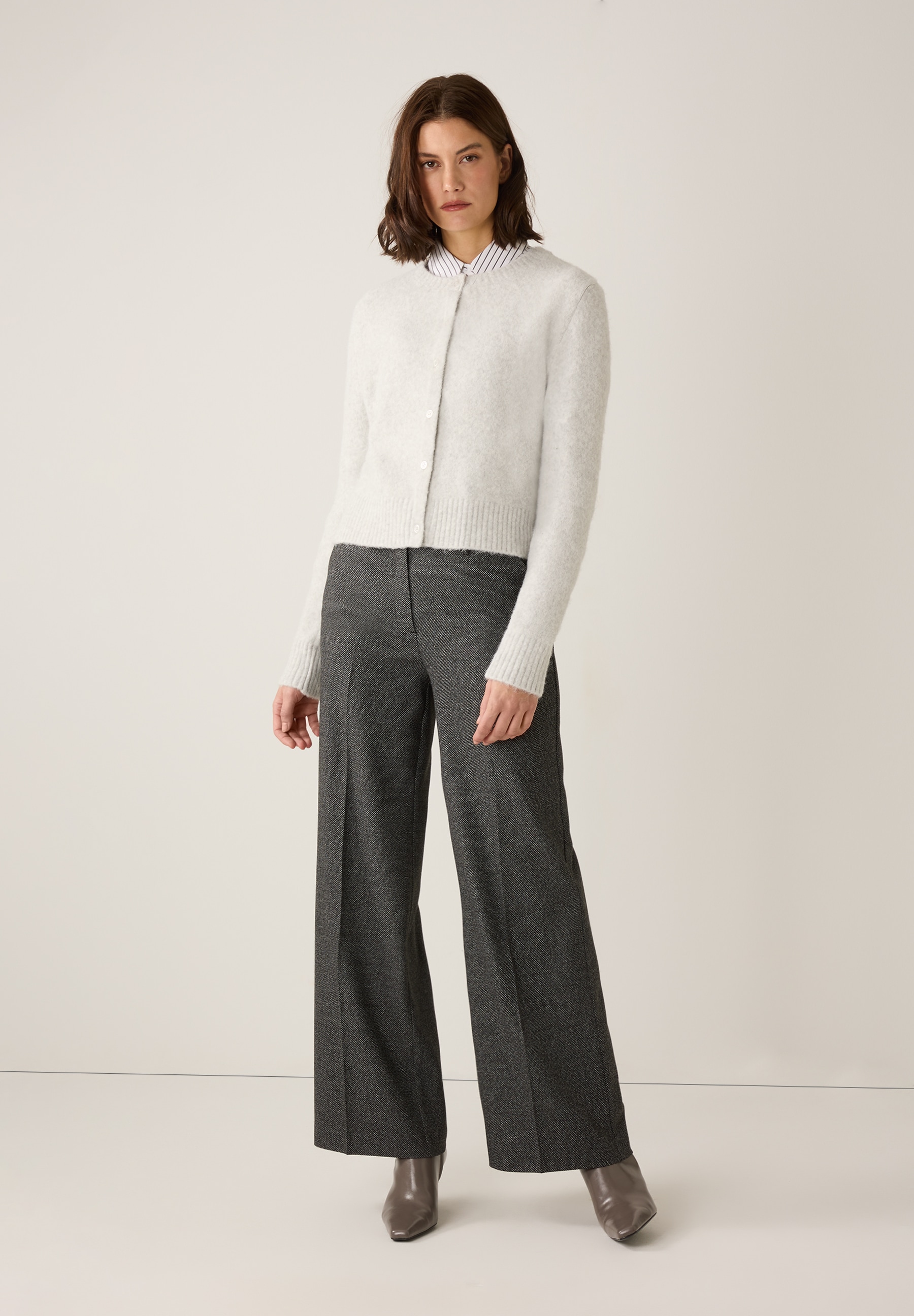 Eine Frau in MORE & MORE Popeline-Bluse mit bequem-elastischer Hose und Stiefeln. Eine Frau in MORE & MORE Popeline-Bluse mit bequem-elastischer Hose und Stiefeln.