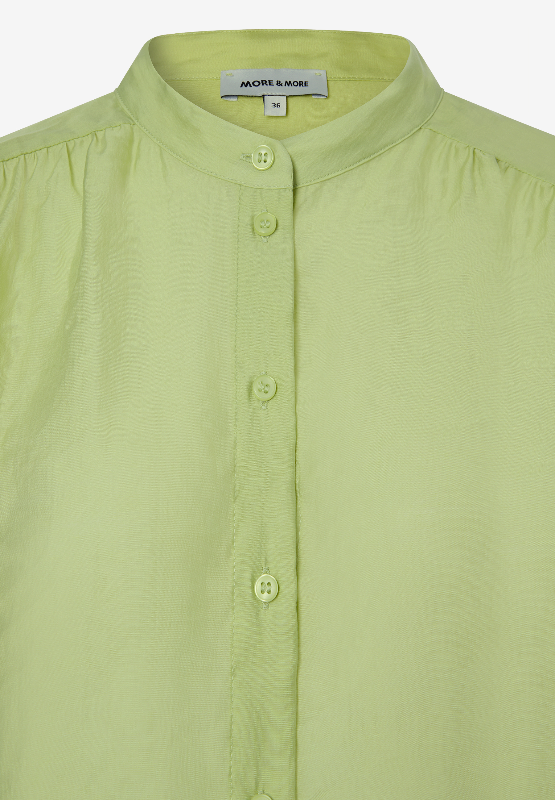 Detailaufnahme einer hellgrünen MORE & MORE Bluse mit Knopfleiste. Detailaufnahme einer hellgrünen MORE & MORE Bluse mit Knopfleiste.