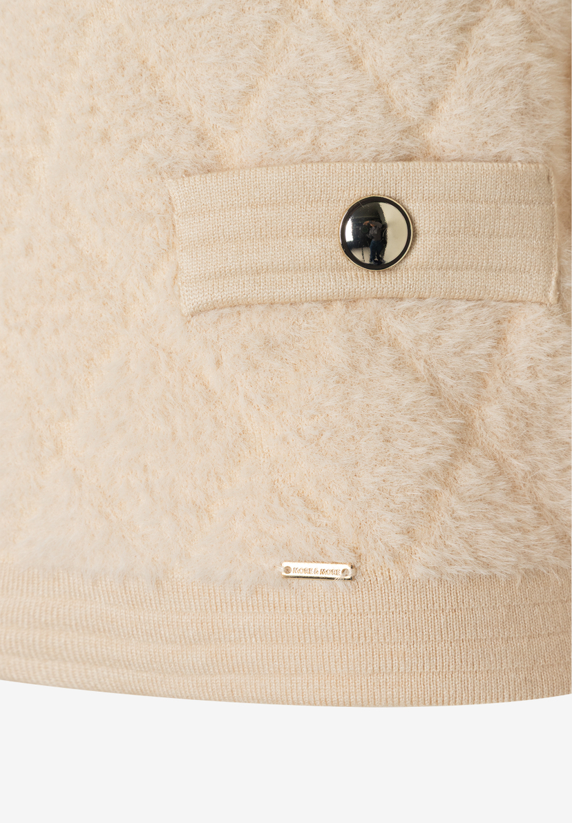 Detailansicht eines MORE & MORE Oberteils aus Kunstfell mit Knopf und Logo. Detailansicht eines MORE & MORE Oberteils aus Kunstfell mit Knopf und Logo.