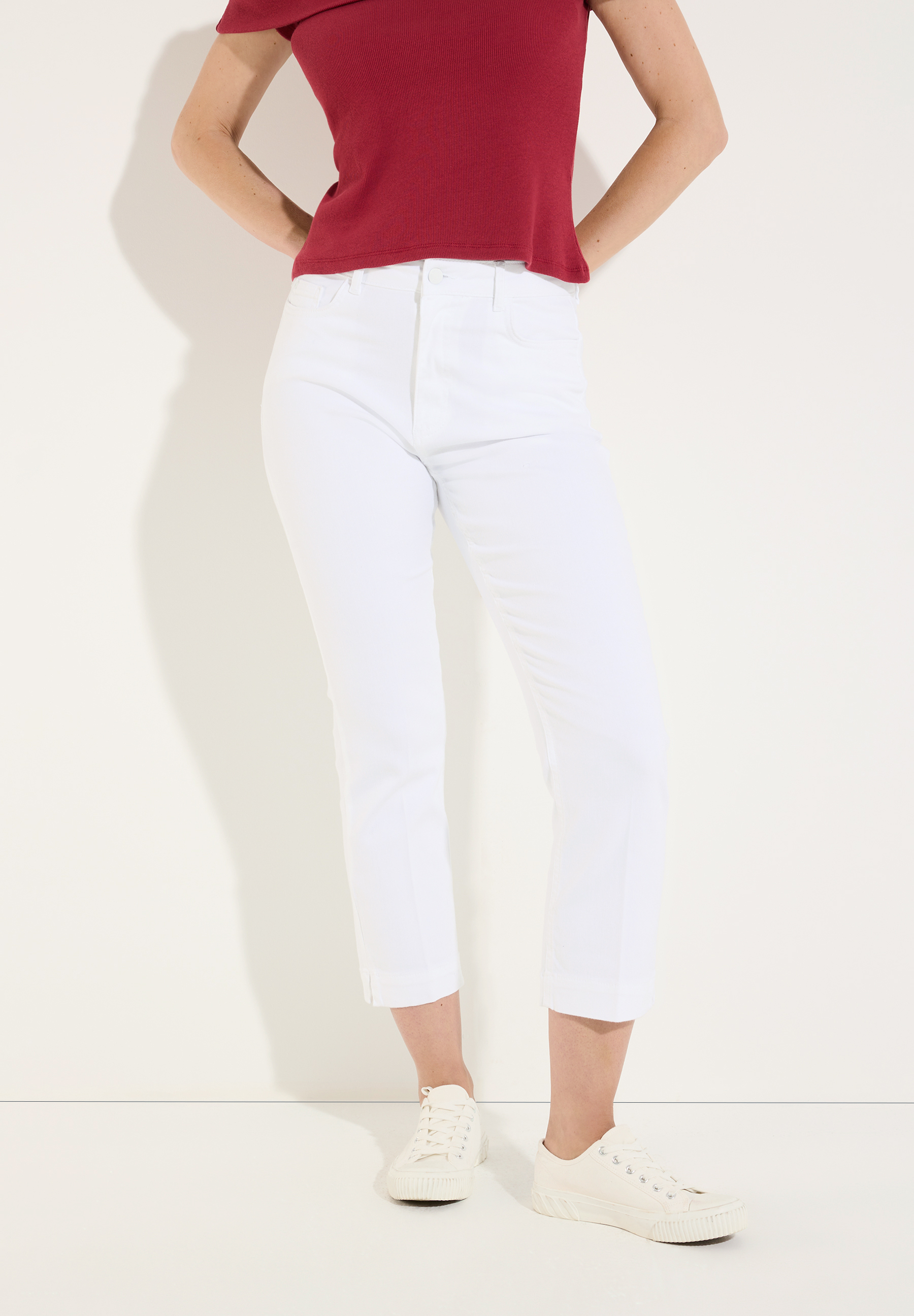 MORE & MORE weiße Denim-Jeans mit weitem Bein und cremefarbenen Sportschuhen. Dazu wird eine Bluse mit braunen Blüten getragen.