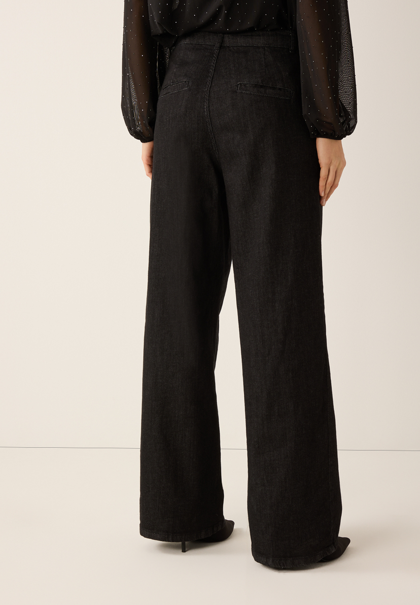 Eine Person trägt MORE & MORE Jeans aus dunklem Denim mit weitem Bein und hoher Taille. Eine Person trägt MORE & MORE Jeans aus dunklem Denim mit weitem Bein und hoher Taille.
