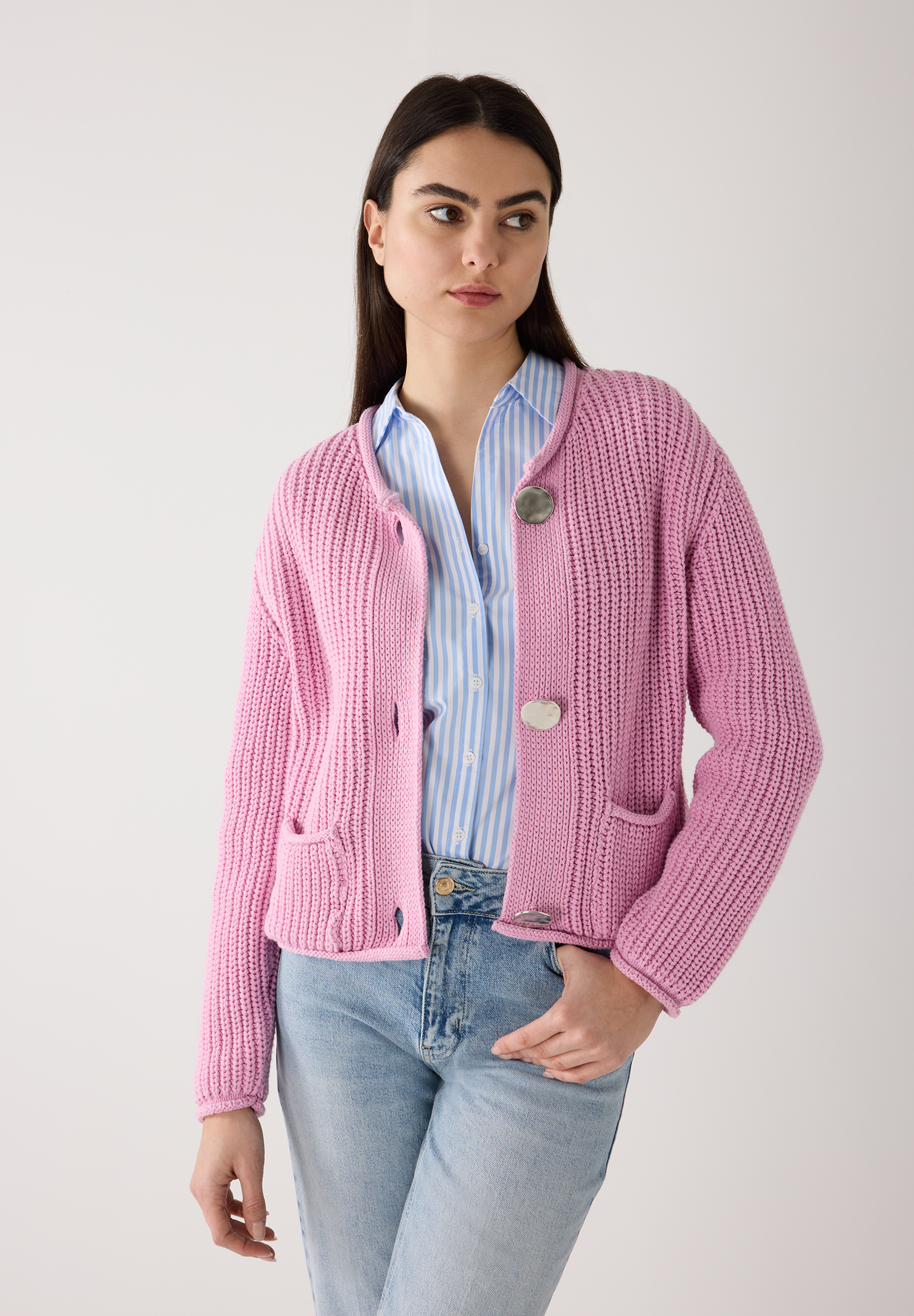 Eine Frau mit einem MORE & MORE Oberteil. Die Rippstrickjacke in Rosa hat Taschen und silberne Knöpfe. Eine Frau mit einem MORE & MORE Oberteil. Die Rippstrickjacke in Rosa hat Taschen und silberne Knöpfe.