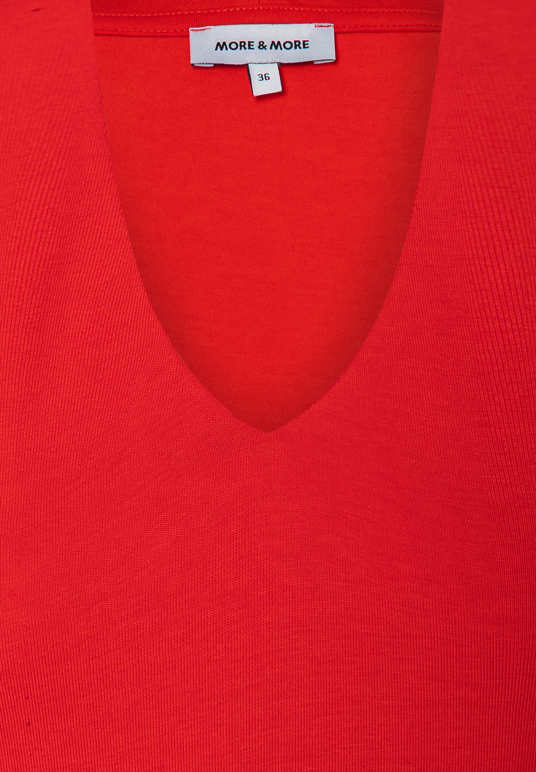 Nahaufnahme eines roten MORE & MORE Oberteils aus Jersey mit V-Ausschnitt. Größe 36. Nahaufnahme eines roten MORE & MORE Oberteils aus Jersey mit V-Ausschnitt. Größe 36.