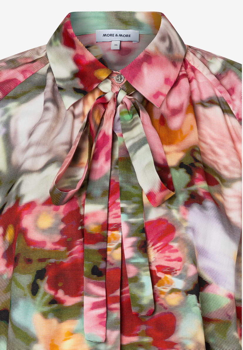 Nahaufnahme einer Bluse von MORE & MORE mit floralem Muster und Schluppe. Nahaufnahme einer Bluse von MORE & MORE mit floralem Muster und Schluppe.
