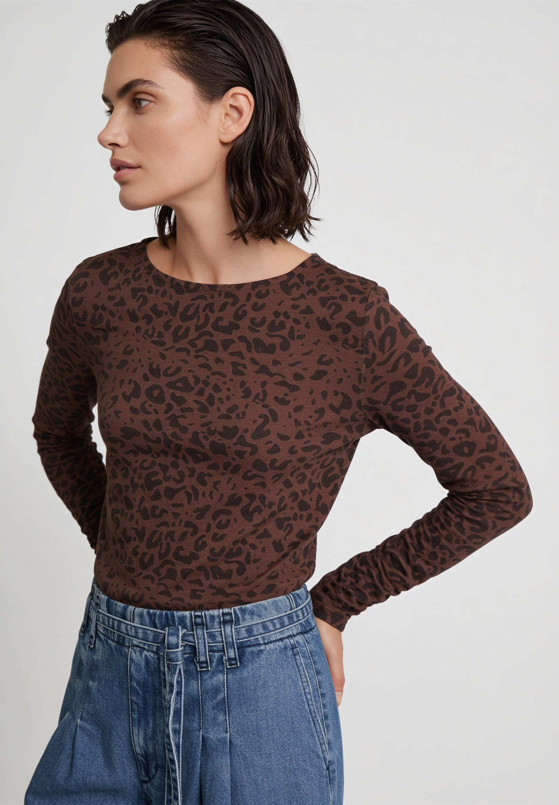 AI generated - MORE & MORE Langarmshirt aus braunem Jersey mit Leopardenmuster, kombiniert mit blauer Jeanshose.