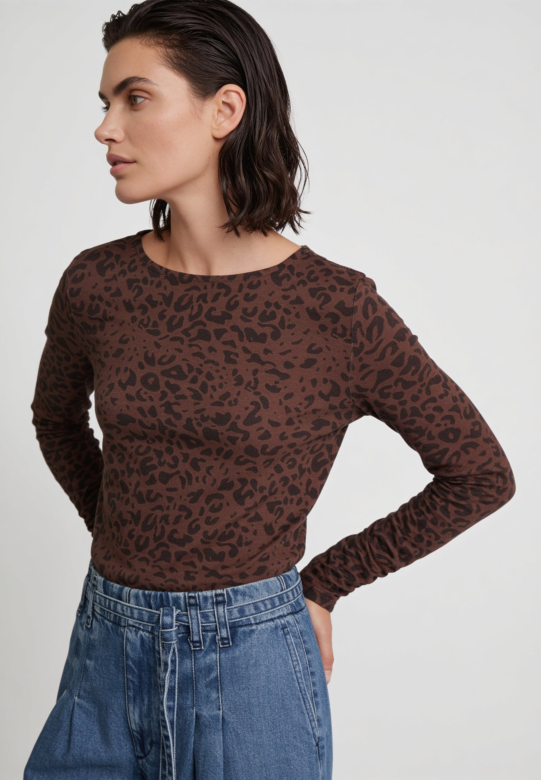 AI generated - MORE & MORE Langarmshirt aus braunem Jersey mit Leopardenmuster, kombiniert mit blauer Jeanshose.