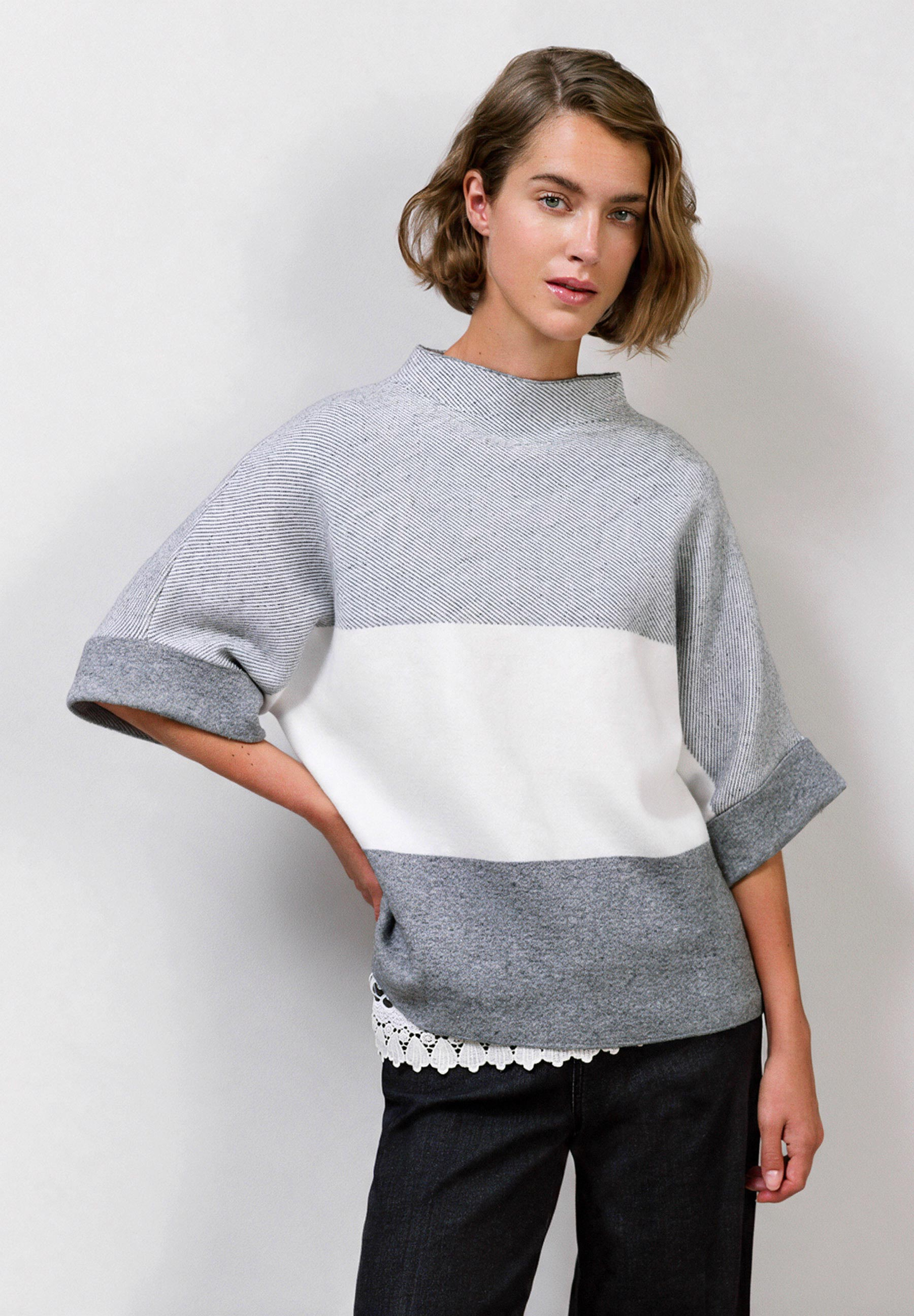 MORE & MORE Pullover: Eine Frau trägt einen schwarz-weiß-grauen Blockfarben-Pullover mit Dreiviertelärmeln.