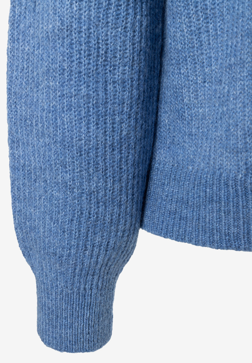 Detailaufnahme des blauen MORE & MORE Pullovers mit Rippenbündchen, hebt die Stricktextur hervor. Detailaufnahme des blauen MORE & MORE Pullovers mit Rippenbündchen, hebt die Stricktextur hervor.
