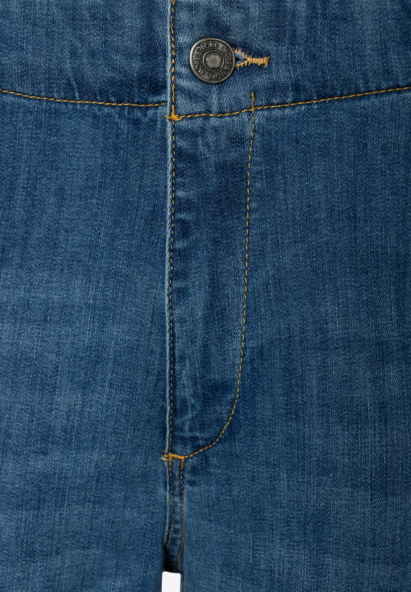Nahaufnahme der MORE & MORE Jeans: Der silberne Knopfverschluss und die gelben Nähte sind im Fokus.