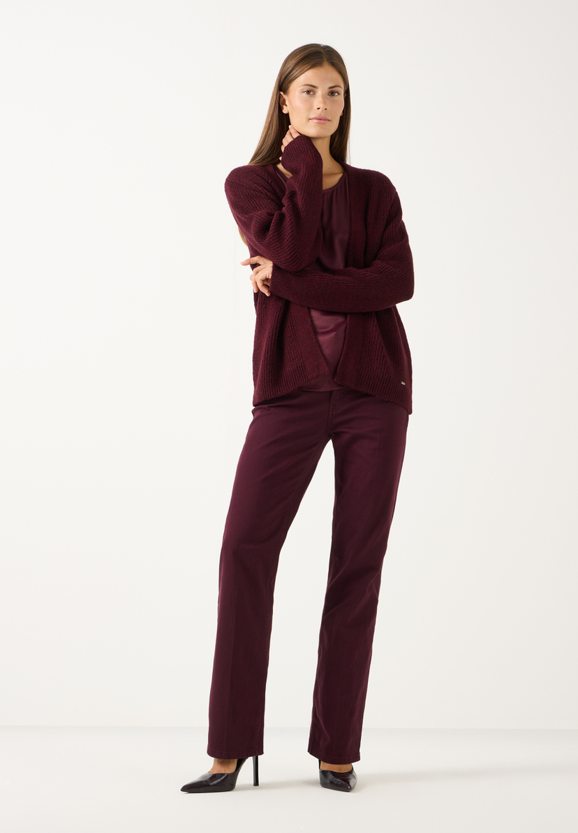 MORE & MORE Jeans: Das Model trägt eine bordeauxrote Jeans und einen passenden Oberteil mit Strickjacke. MORE & MORE Jeans: Das Model trägt eine bordeauxrote Jeans und einen passenden Oberteil mit Strickjacke.