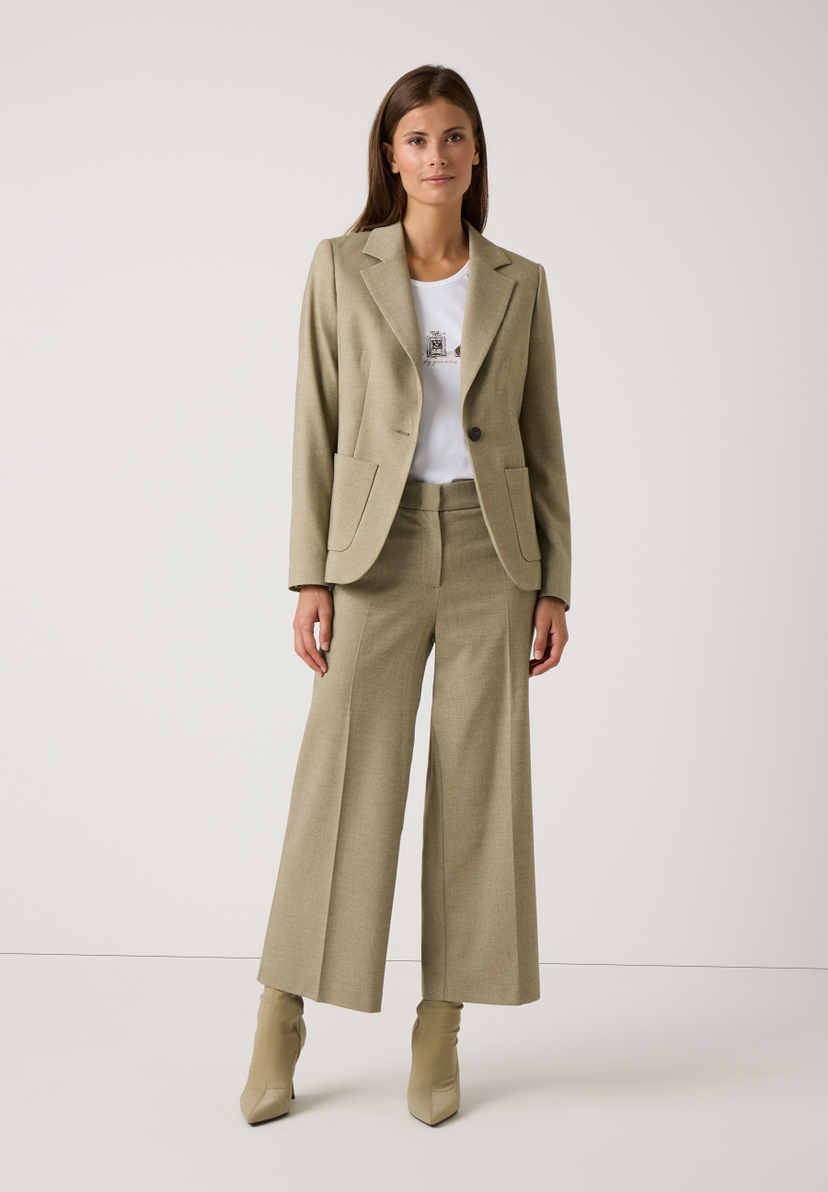 Eine Frau in einem olivgrünen Hosenanzug und MORE & MORE Oberteil mit Jersey-Materialkonstruktion. Eine Frau in einem olivgrünen Hosenanzug und MORE & MORE Oberteil mit Jersey-Materialkonstruktion.