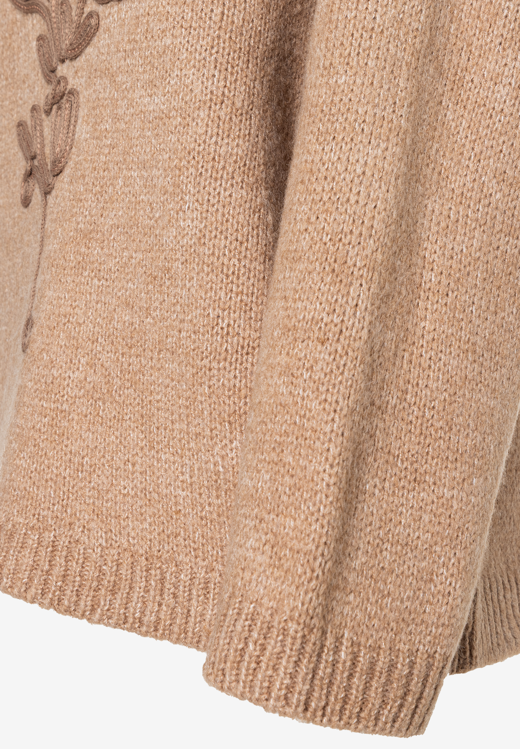 Nahaufnahme eines beigen MORE & MORE Pullovers mit floralen Stickereien am Ärmel. Nahaufnahme eines beigen MORE & MORE Pullovers mit floralen Stickereien am Ärmel.