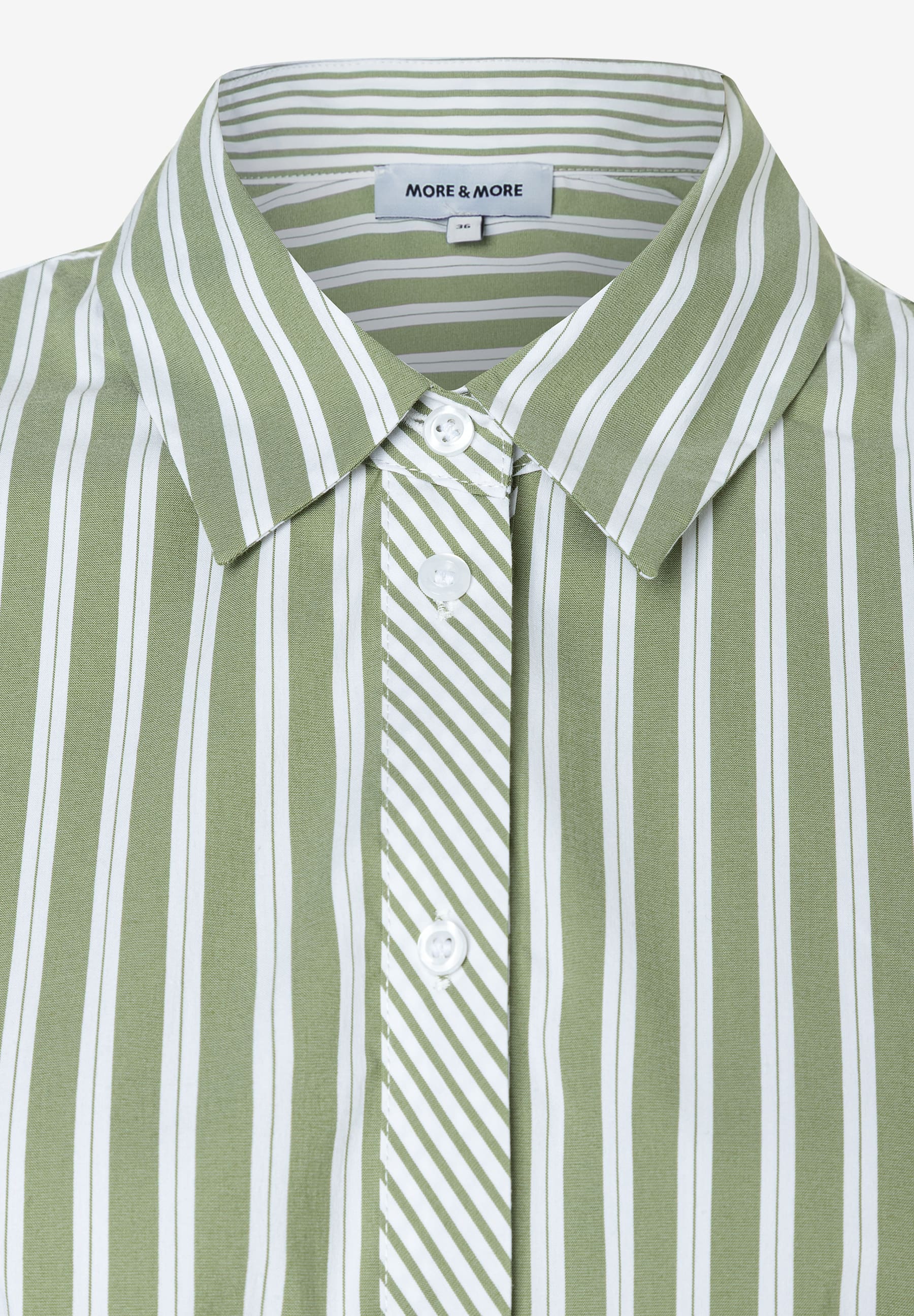 Nahaufnahme einer MORE & MORE Bluse. Das Oberteil ist grün-weiß gestreift und hat weiße Knöpfe. Nahaufnahme einer MORE & MORE Bluse. Das Oberteil ist grün-weiß gestreift und hat weiße Knöpfe.
