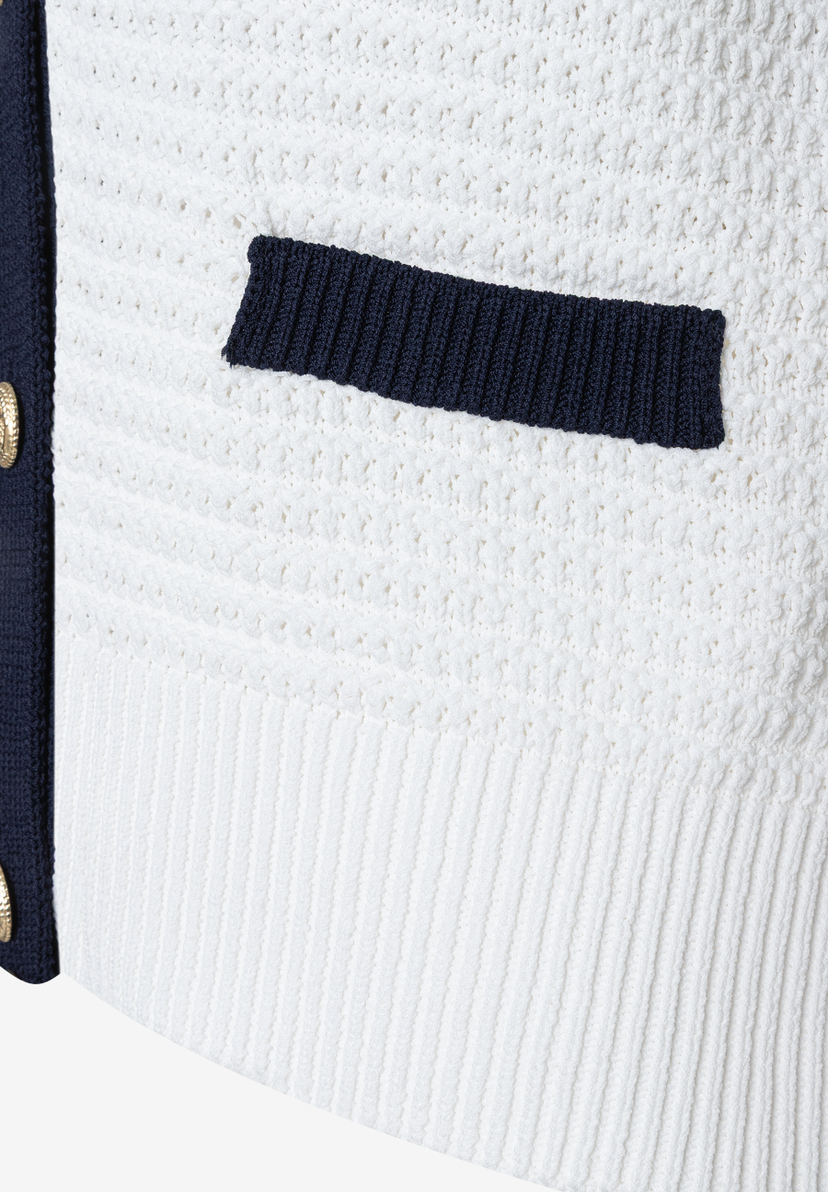 Nahaufnahme eines weißen MORE & MORE Strickoberteils mit blauer Paspelierung und kleiner Tasche. Nahaufnahme eines weißen MORE & MORE Strickoberteils mit blauer Paspelierung und kleiner Tasche.