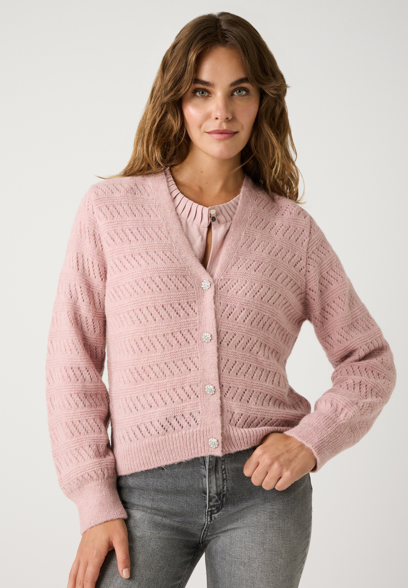Eine Frau trägt einen rosa Lochstrick-Cardigan der Marke MORE & MORE mit glitzernden Knöpfen und eine graue Jeans. Eine Frau trägt einen rosa Lochstrick-Cardigan der Marke MORE & MORE mit glitzernden Knöpfen und eine graue Jeans.