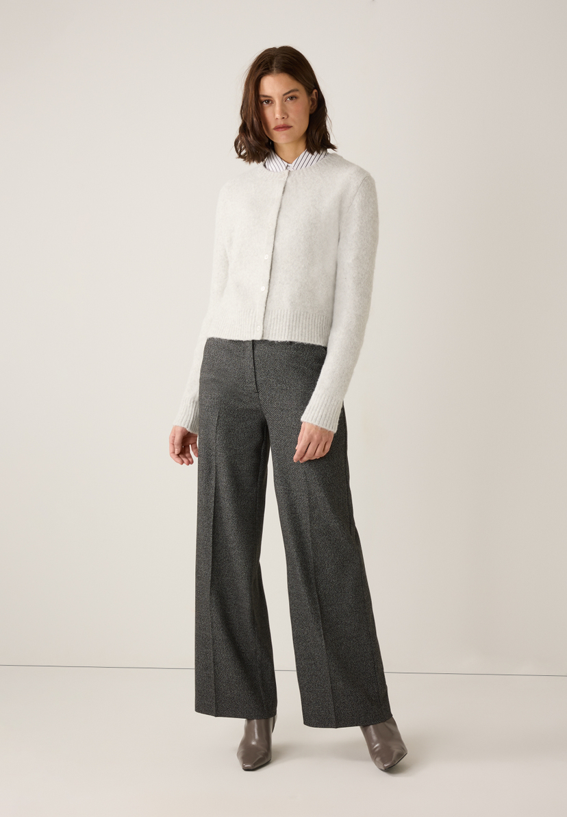Eine Frau trägt einen MORE & MORE Cardigan, eine gestreifte Bluse und eine graue Hose. Eine Frau trägt einen MORE & MORE Cardigan, eine gestreifte Bluse und eine graue Hose.