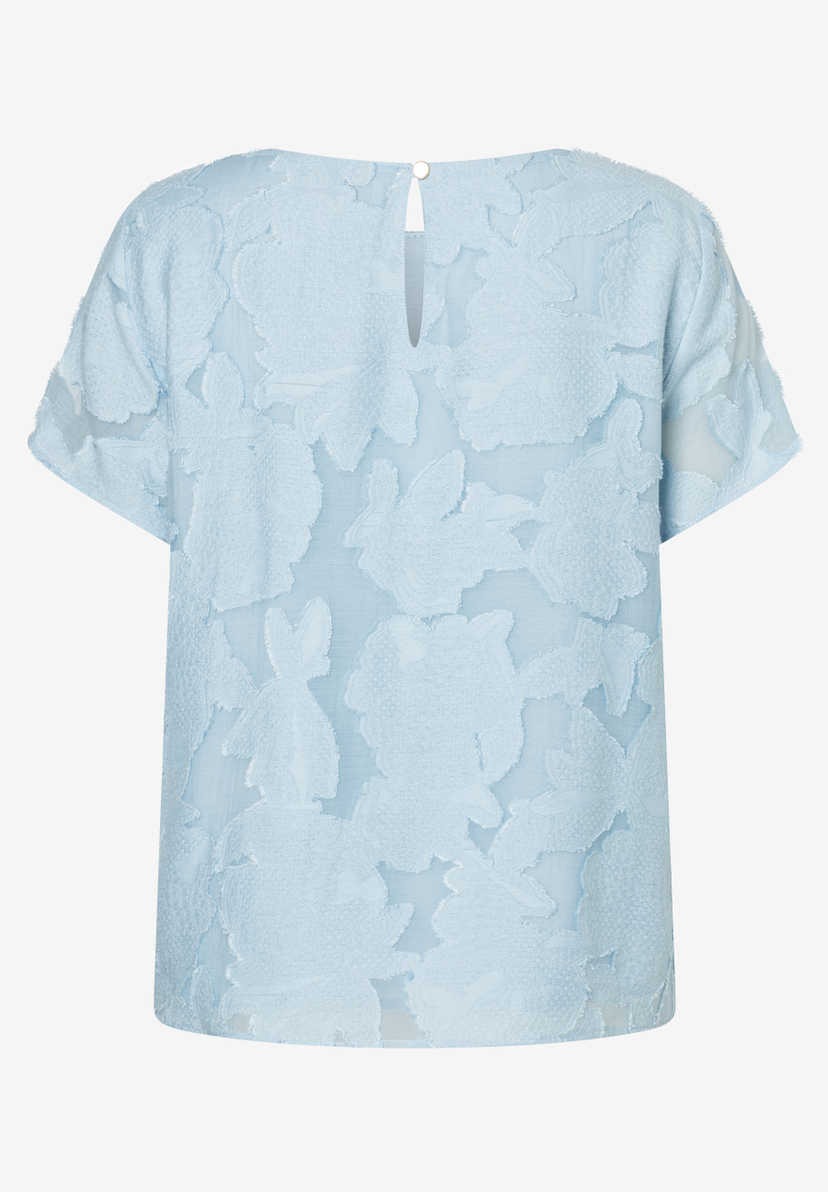 Hellblaue, kurzärmlige MORE & MORE Bluse mit floraler Struktur und Knopf am Rückenausschnitt. Hellblaue, kurzärmlige MORE & MORE Bluse mit floraler Struktur und Knopf am Rückenausschnitt.
