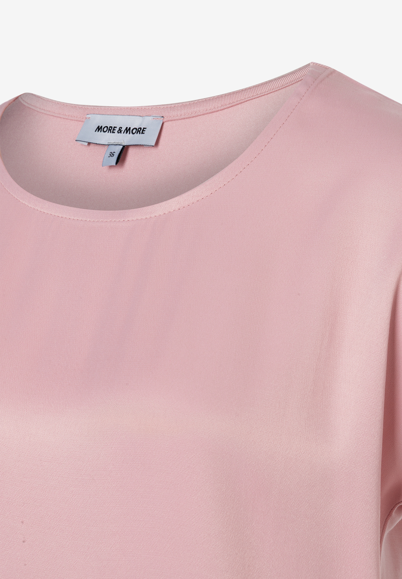 Nahaufnahme eines MORE & MORE Oberteils mit Rundhalsausschnitt in zartem Rosa. Ein Etikett ist sichtbar. Nahaufnahme eines MORE & MORE Oberteils mit Rundhalsausschnitt in zartem Rosa. Ein Etikett ist sichtbar.