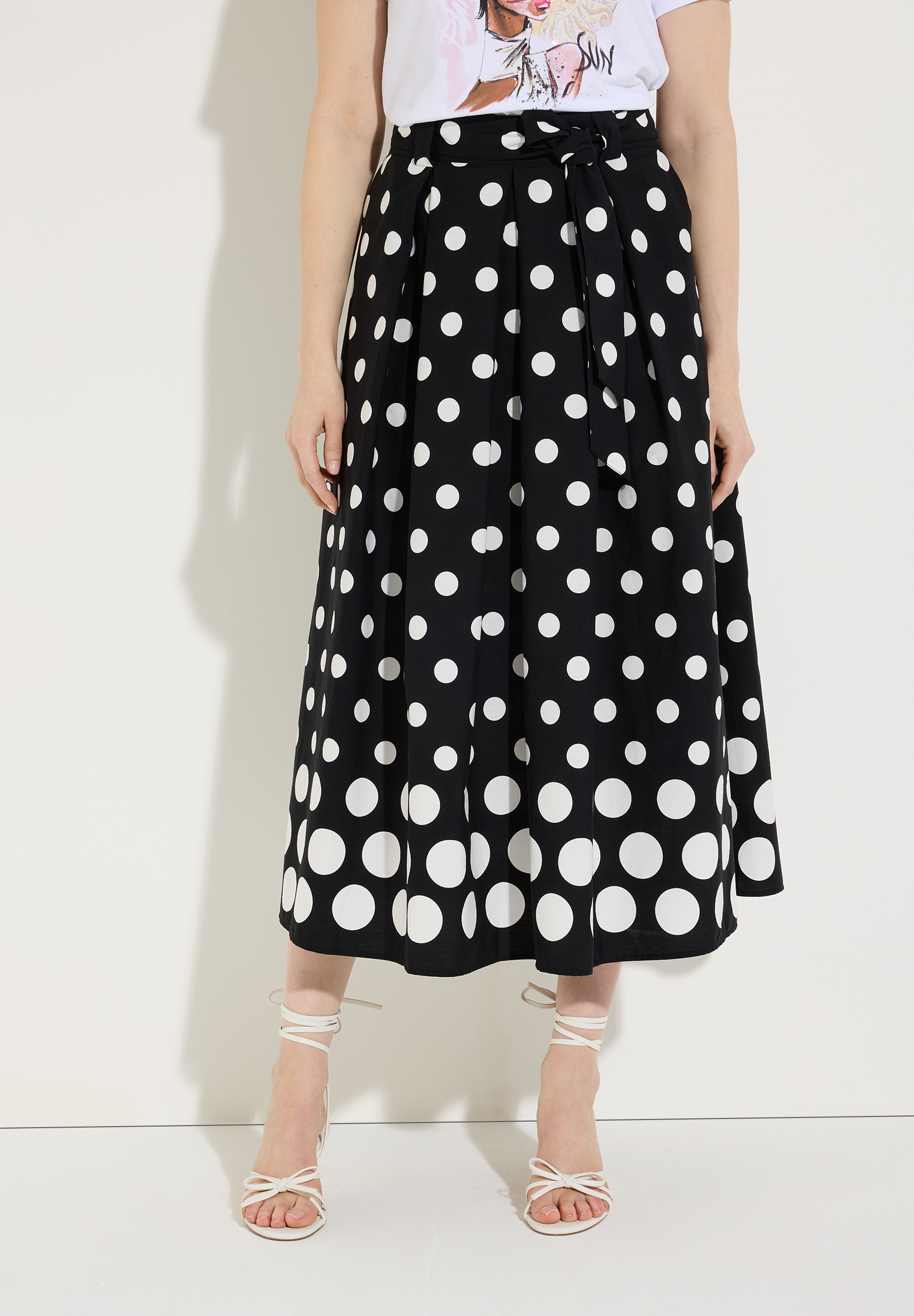 Ein Rock von MORE & MORE mit weißem Punktmuster auf schwarzem Grund, aus Popeline.