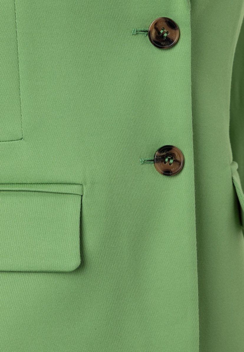Nahaufnahme eines grünen MORE & MORE Blazers mit Knöpfen und Tasche. Nahaufnahme eines grünen MORE & MORE Blazers mit Knöpfen und Tasche.