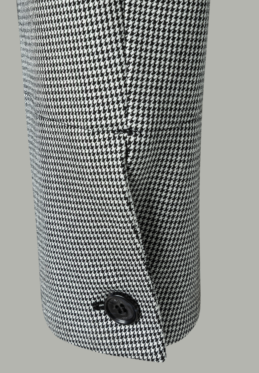 Detailansicht eines MORE & MORE Blazers mit Hahnentrittmuster und Knopf am Ärmel. Detailansicht eines MORE & MORE Blazers mit Hahnentrittmuster und Knopf am Ärmel.