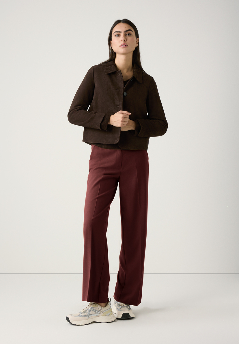 Eine Frau trägt einen braunen Rippstrick-Pullover von MORE & MORE mit V-Ausschnitt. Das Material wirkt weich und wärmend. Eine Frau trägt einen braunen Rippstrick-Pullover von MORE & MORE mit V-Ausschnitt. Das Material wirkt weich und wärmend.