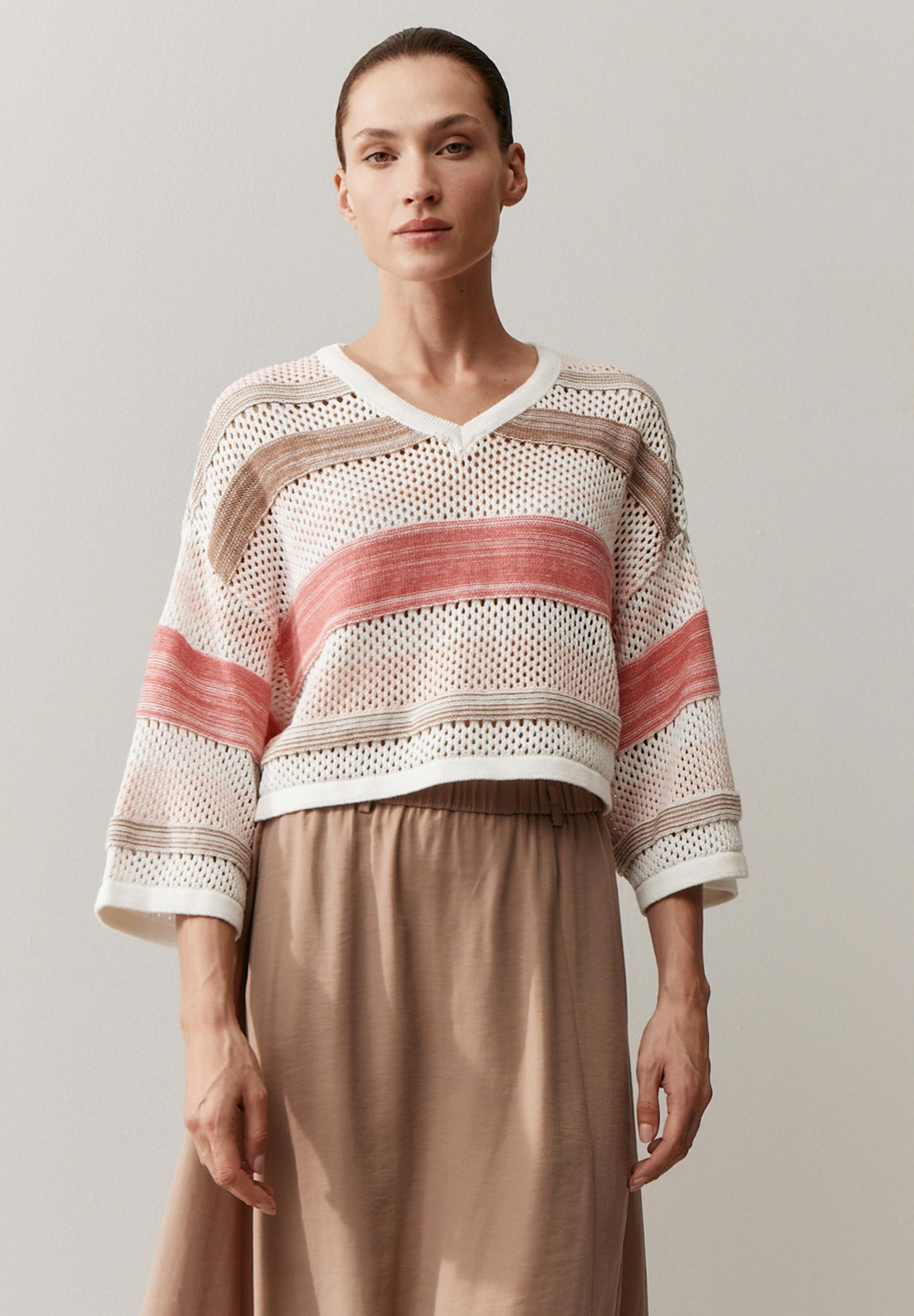 Eine Frau zeigt einen MORE & MORE Pullover mit Streifen und V-Ausschnitt.