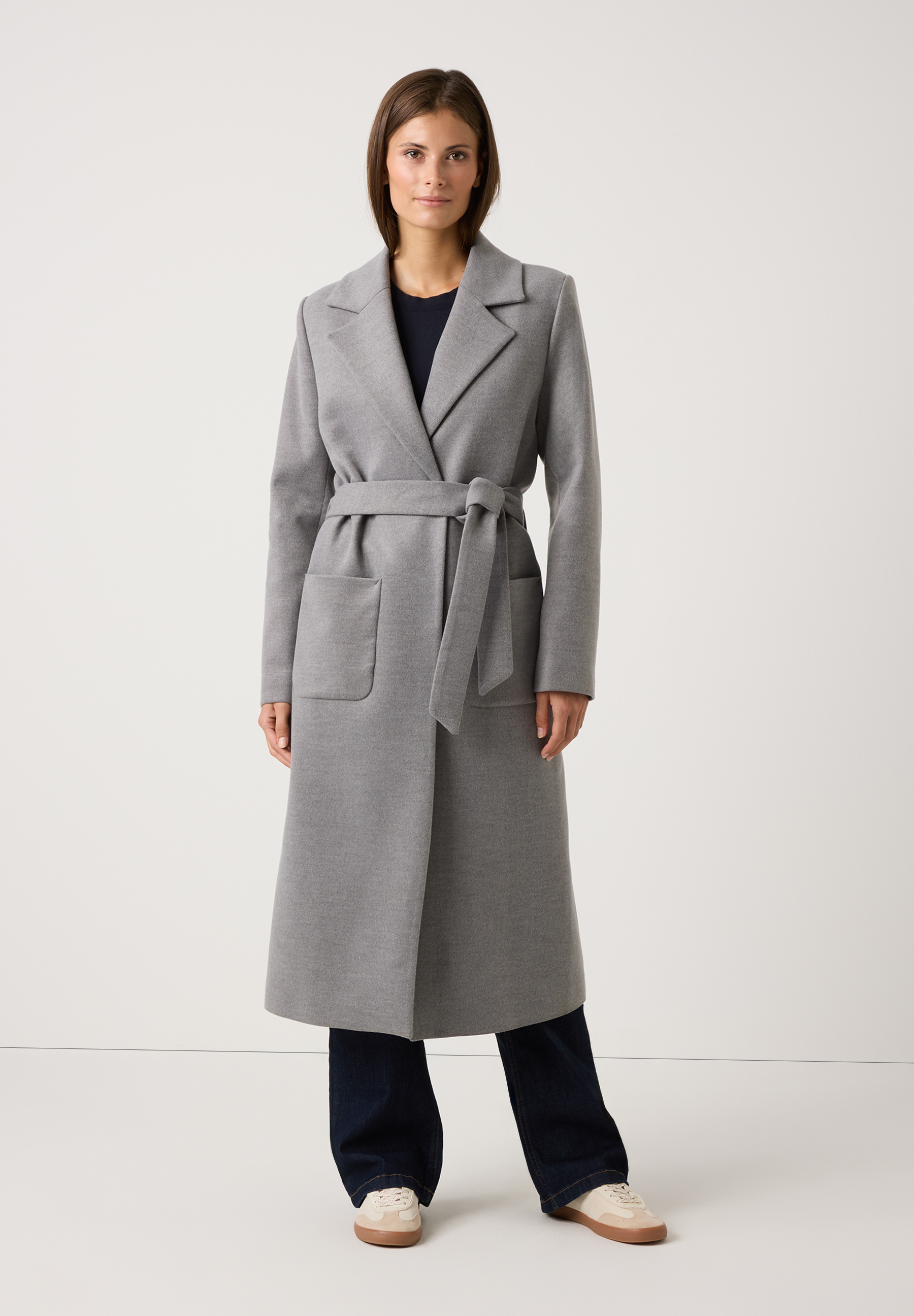 Eine Frau trägt einen grauen MORE & MORE-Mantel mit Bindegürtel. Webware für angenehmen Tragekomfort. Eine Frau trägt einen grauen MORE & MORE-Mantel mit Bindegürtel. Webware für angenehmen Tragekomfort.