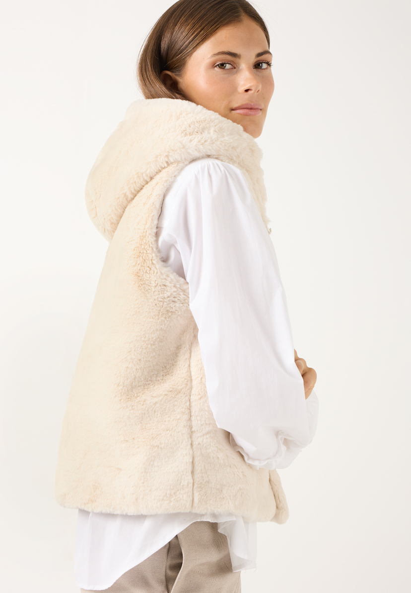 MORE & MORE Weste aus Shearling-Imitat. Eine junge Frau trägt eine weiße Bluse und eine beigefarbene Weste mit Kapuze. MORE & MORE Weste aus Shearling-Imitat. Eine junge Frau trägt eine weiße Bluse und eine beigefarbene Weste mit Kapuze.