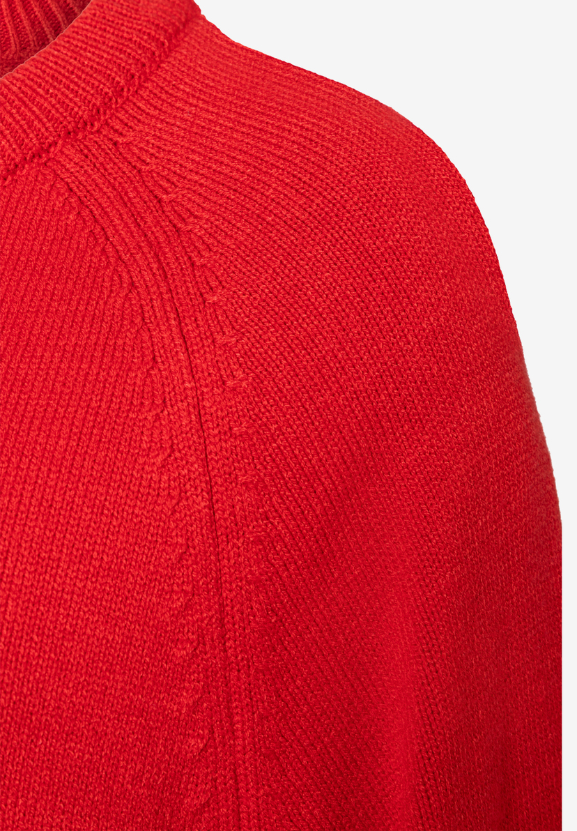 Nahaufnahme eines roten Strickpullovers von MORE & MORE, der angenehm und elastisch ist. Nahaufnahme eines roten Strickpullovers von MORE & MORE, der angenehm und elastisch ist.