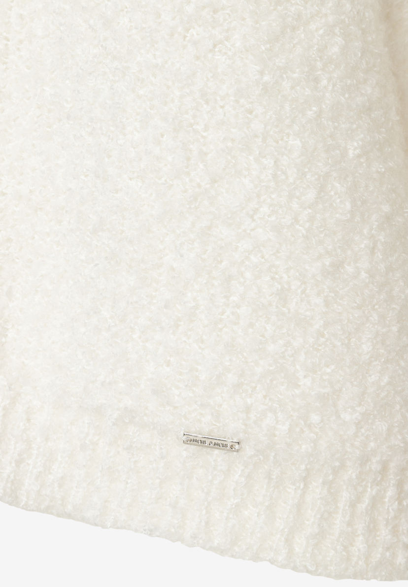 Nahaufnahme eines weißen, wärmenden Bouclé-Oberteils von MORE & MORE mit kleinem Logo-Etikett. Nahaufnahme eines weißen, wärmenden Bouclé-Oberteils von MORE & MORE mit kleinem Logo-Etikett.