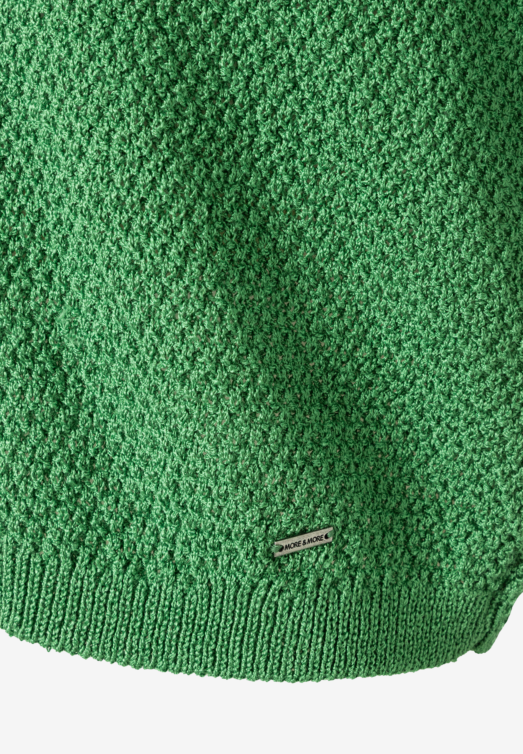 Nahaufnahme eines grünen MORE & MORE Strickpullovers mit feiner Textur und Logo-Etikett. Nahaufnahme eines grünen MORE & MORE Strickpullovers mit feiner Textur und Logo-Etikett.