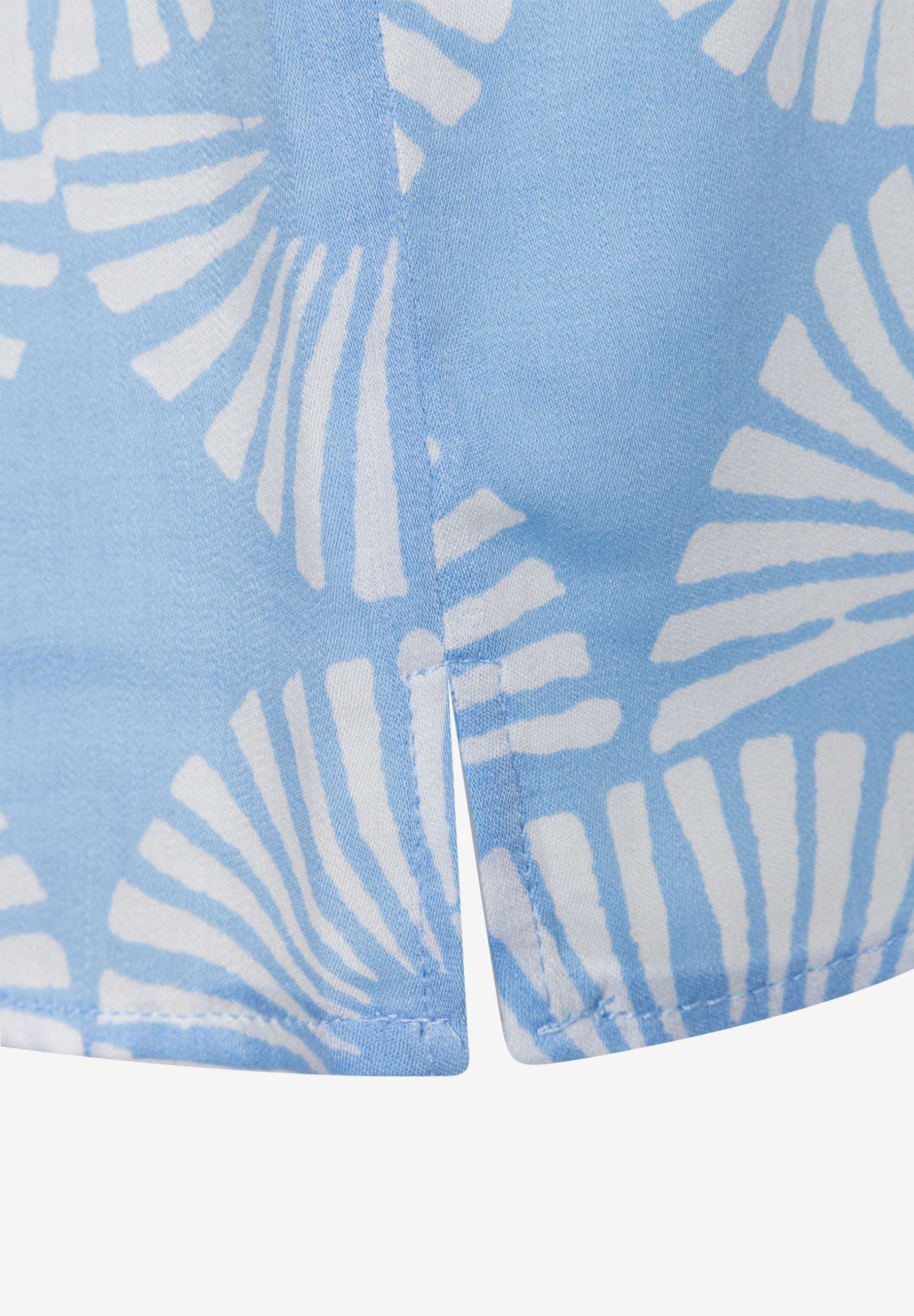 Nahaufnahme einer MORE & MORE Bluse mit blau-weißem Muster und seitlichem Saumschlitz. Nahaufnahme einer MORE & MORE Bluse mit blau-weißem Muster und seitlichem Saumschlitz.