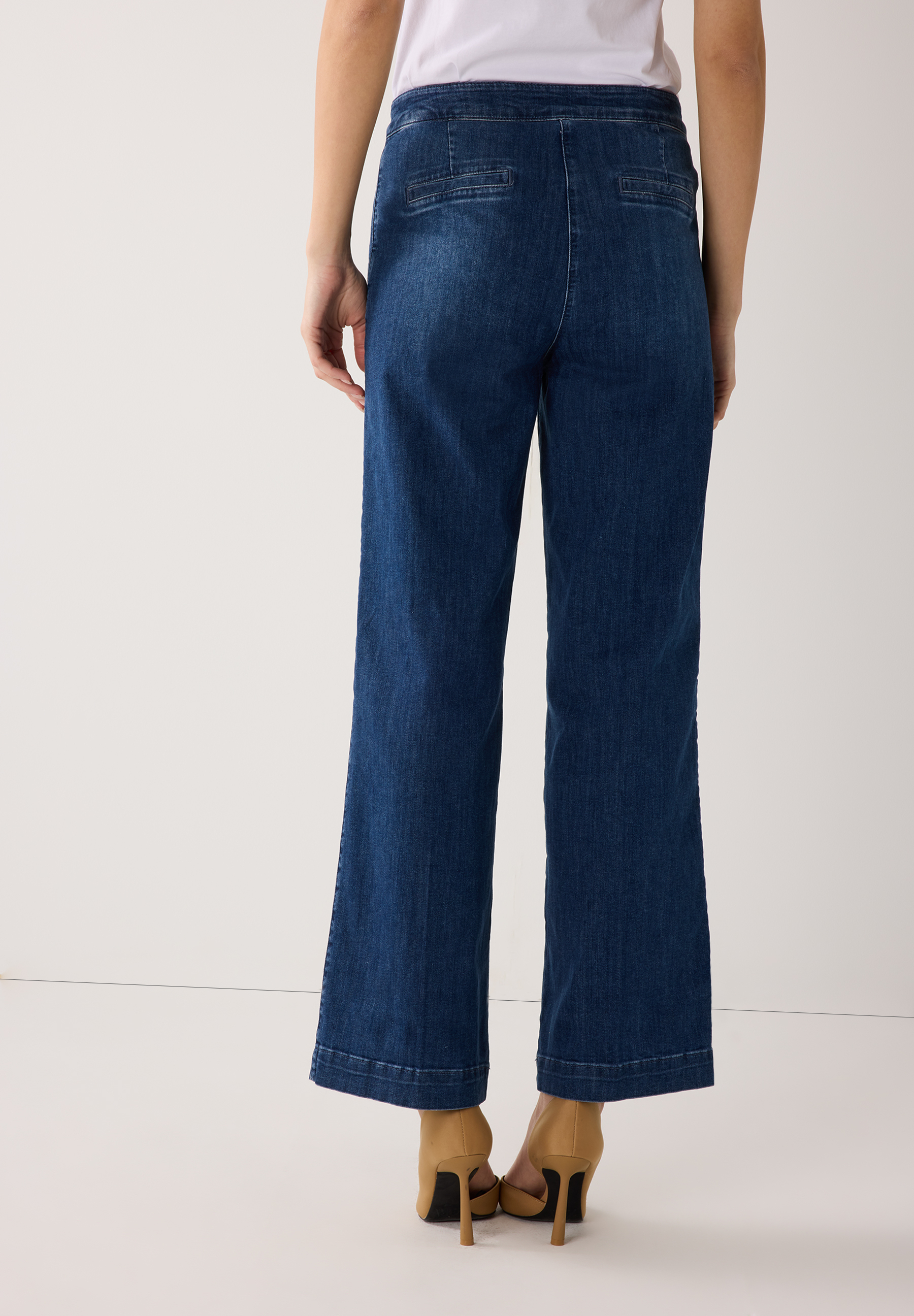 Rückansicht einer Person, die MORE & MORE Jeans aus Denim und Schuhe trägt. Rückansicht einer Person, die MORE & MORE Jeans aus Denim und Schuhe trägt.