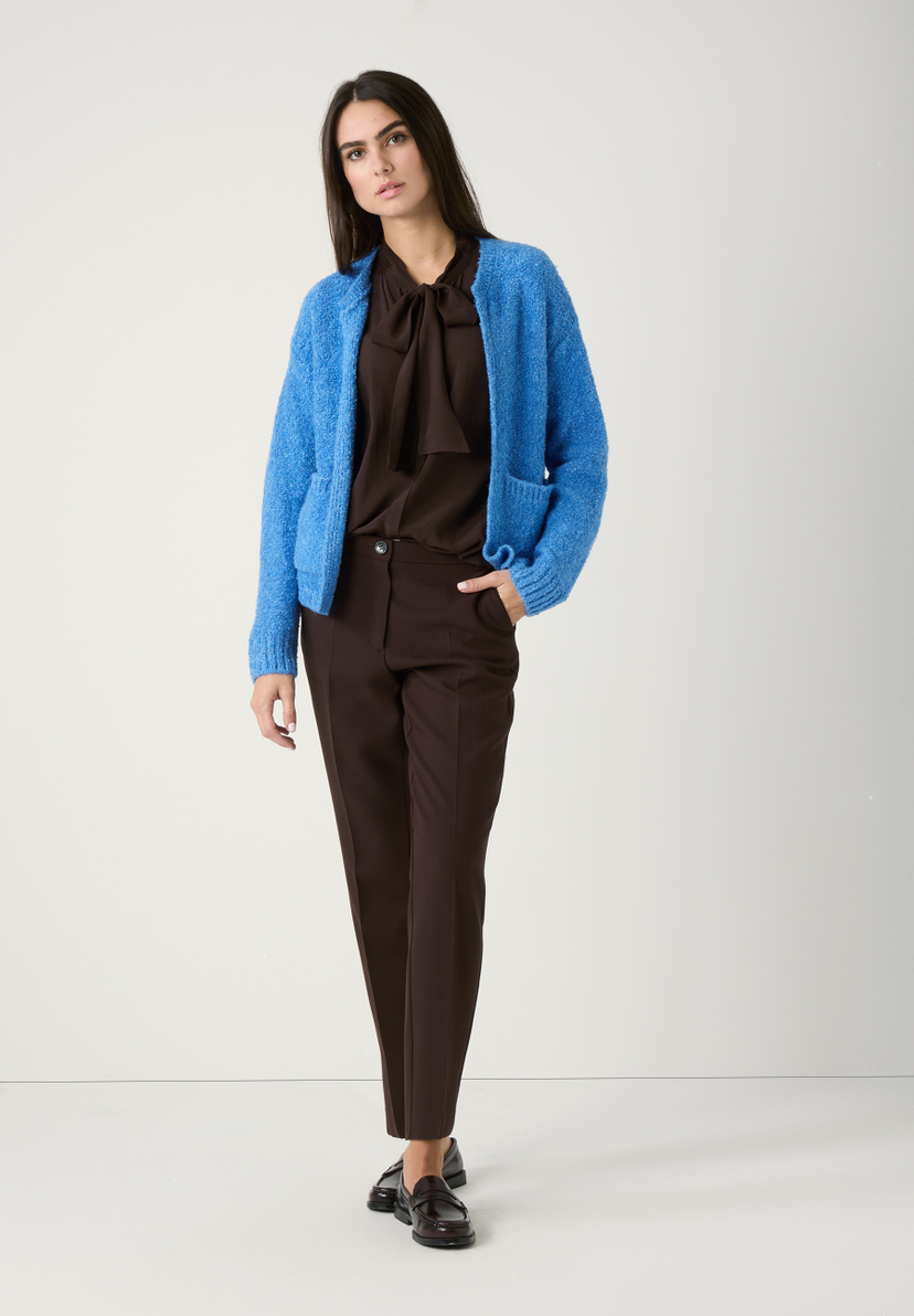 Eine Frau im MORE & MORE Strick-Bouclé-Look: blaue Strickjacke, braune Bluse mit Schleife, Hose und Schuhe. Komfortabler, warmer Griff. Eine Frau im MORE & MORE Strick-Bouclé-Look: blaue Strickjacke, braune Bluse mit Schleife, Hose und Schuhe. Komfortabler, warmer Griff.