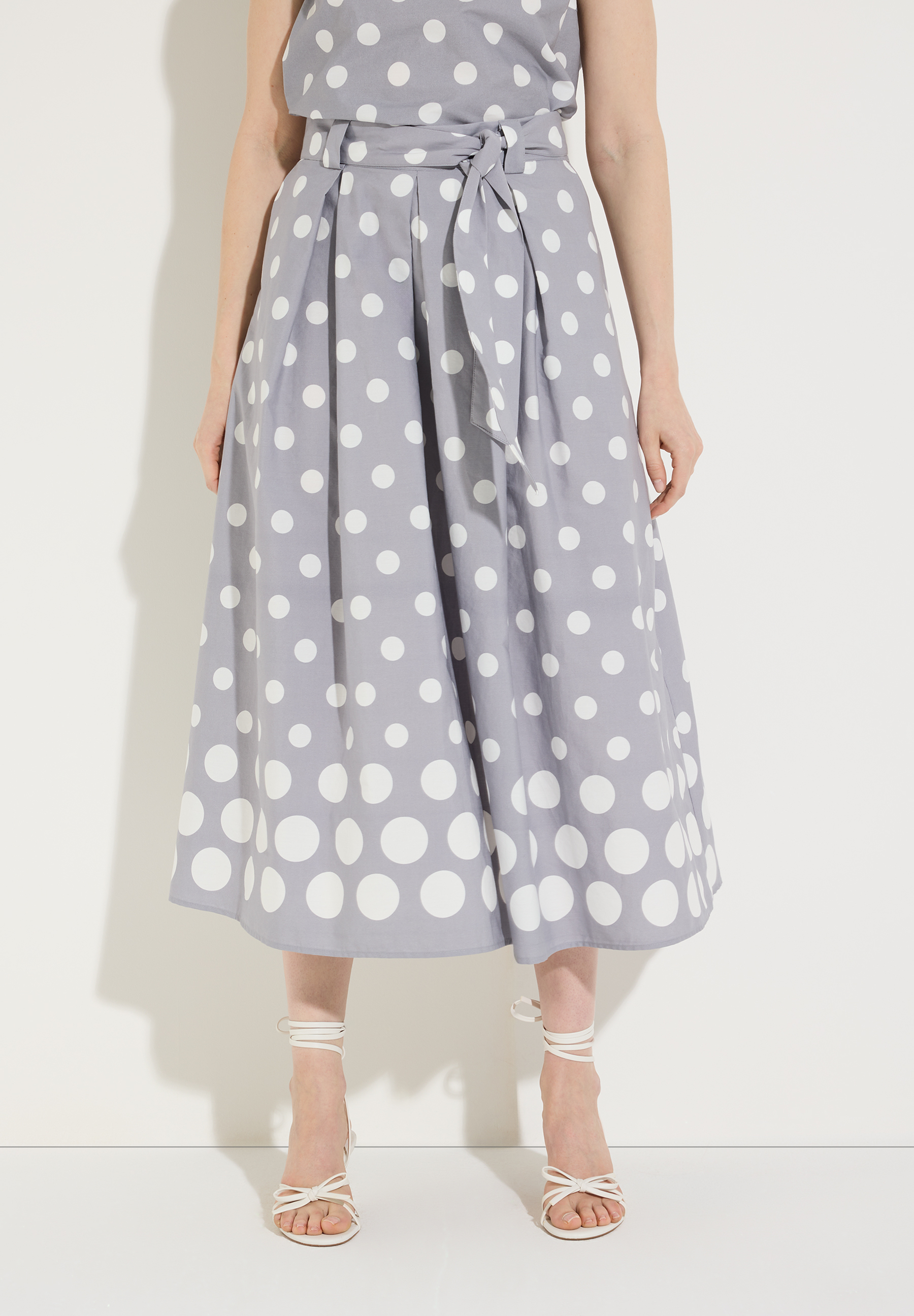 Ein MORE & MORE Rock, knielang, hellgrau mit weißen Punkten und Bindegürtel.