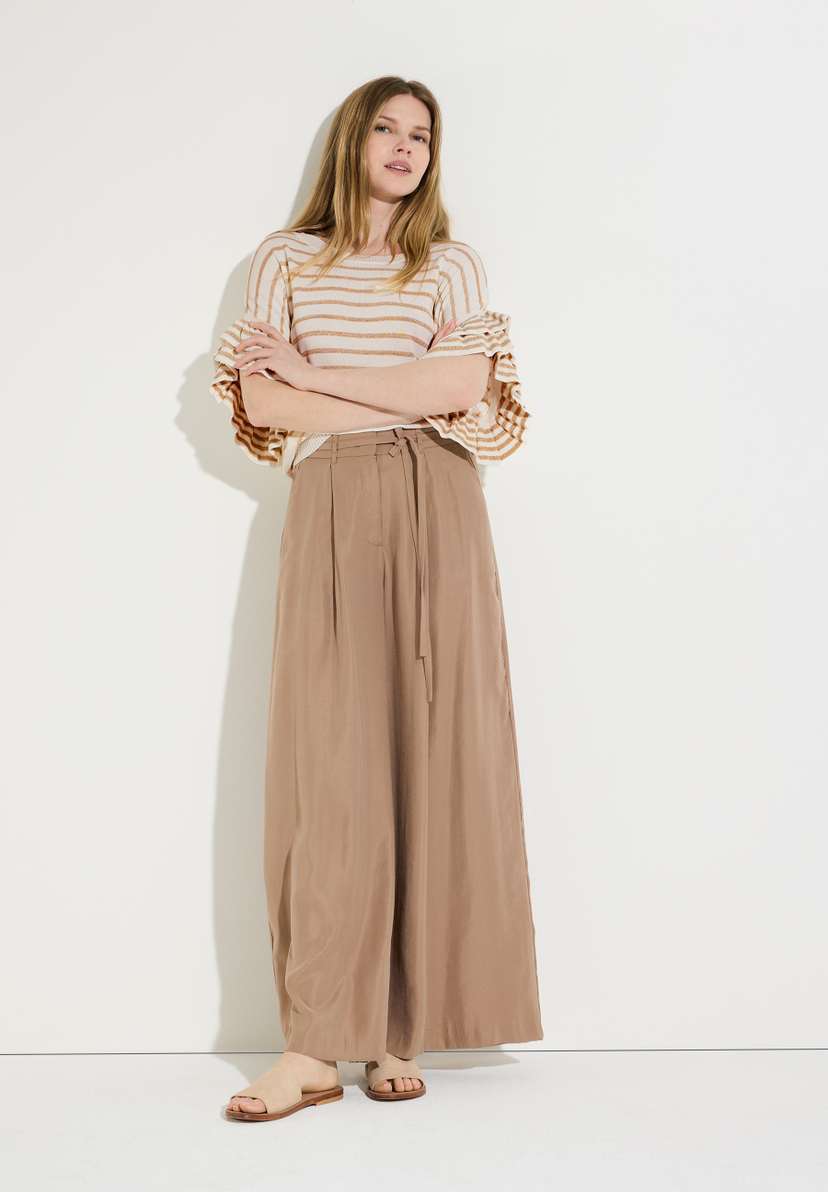 Eine Frau mit langem, blondem Haar trägt einen gestreiften Strickpullover von MORE & MORE und eine weite Hose. Eine Frau mit langem, blondem Haar trägt einen gestreiften Strickpullover von MORE & MORE und eine weite Hose.