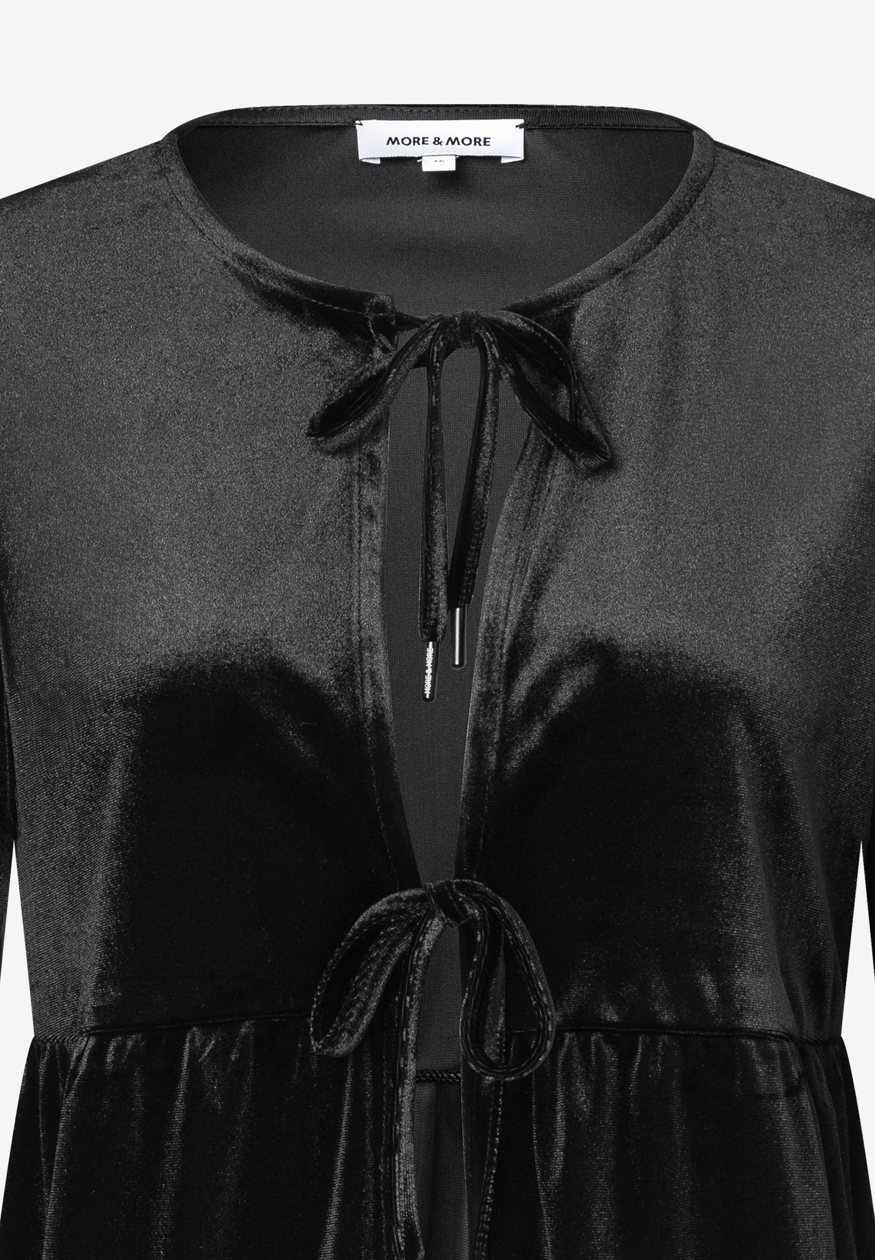 Ein schwarzes Samt-Top von MORE & MORE mit Bindebändern am Ausschnitt. Ein schwarzes Samt-Top von MORE & MORE mit Bindebändern am Ausschnitt.