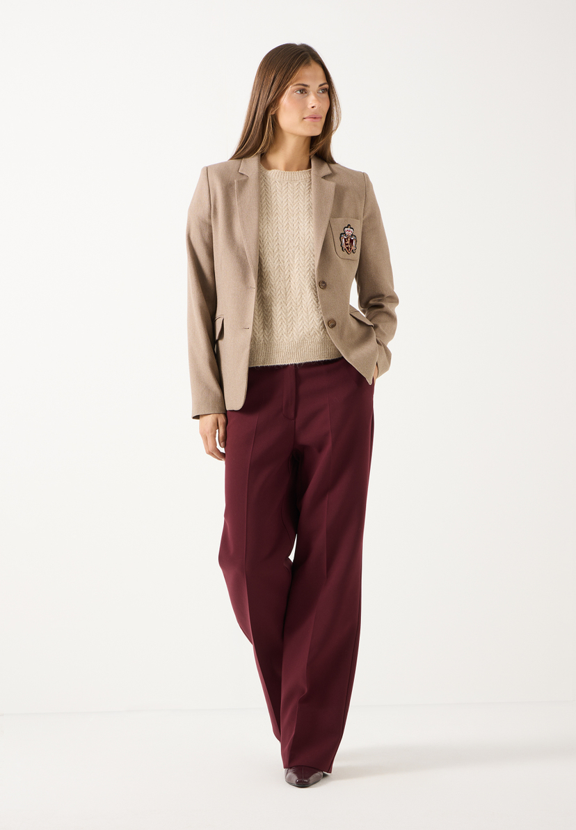 MORE & MORE Jeans: Stilvolle kastanienbraune Hose, kombiniert mit einem beigen Pullover und einer beigen Jacke, die ein Wappen trägt.