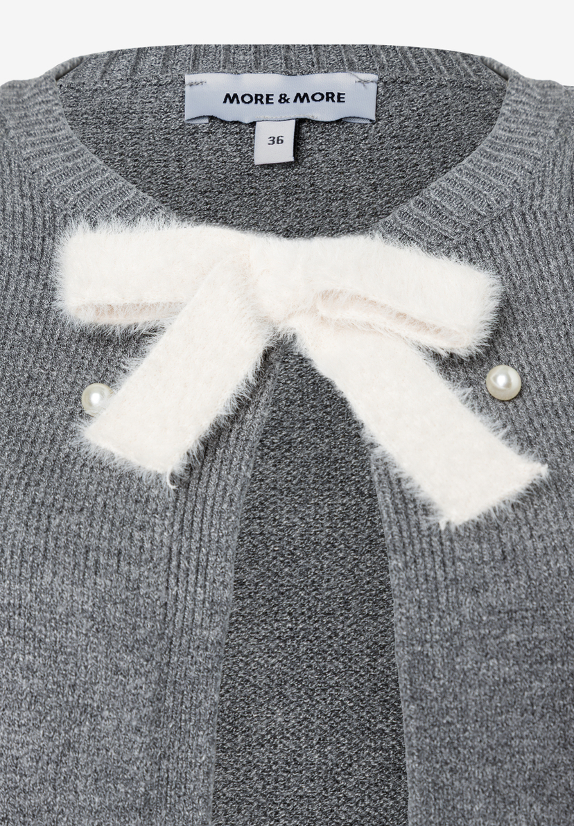 Detailaufnahme einer grauen MORE & MORE Strickjacke mit Schleife und Perlenknöpfen. Detailaufnahme einer grauen MORE & MORE Strickjacke mit Schleife und Perlenknöpfen.