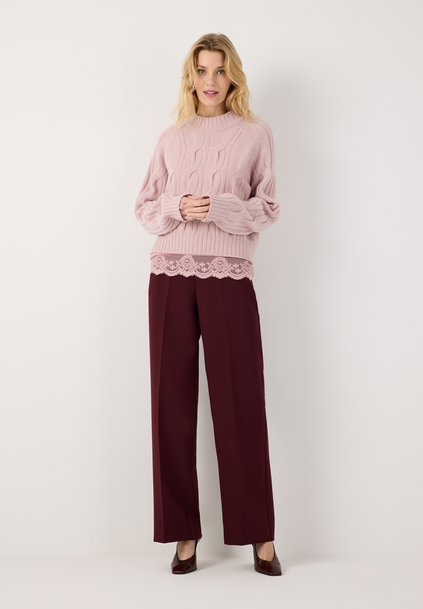 MORE & MORE Pullover in Zopfstrick, rosa, mit weinroter Hose und rosa Spitzen-Top. Model lächelt. MORE & MORE Pullover in Zopfstrick, rosa, mit weinroter Hose und rosa Spitzen-Top. Model lächelt.