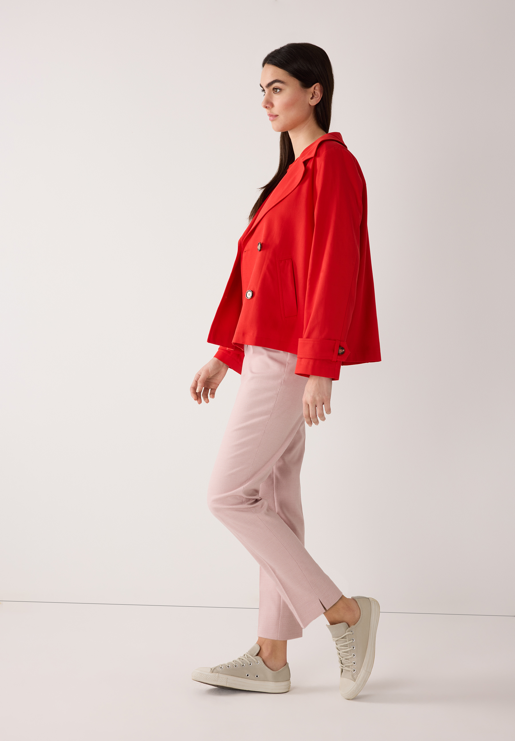 Eine Frau in roter MORE & MORE Jacke aus Twill mit angenehmem Tragekomfort, kombinierrt mit rosafarbener Hose und Sneakern. Eine Frau in roter MORE & MORE Jacke aus Twill mit angenehmem Tragekomfort, kombinierrt mit rosafarbener Hose und Sneakern.