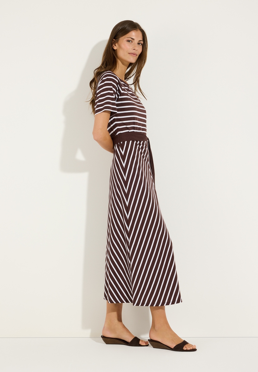 MORE & MORE Jersey-Kleid gestreift. Modell trägt ein braunes Kleid mit weißen Querstreifen oben und diagonalen Streifen unten, dazu braune Sandalen. MORE & MORE Jersey-Kleid gestreift. Modell trägt ein braunes Kleid mit weißen Querstreifen oben und diagonalen Streifen unten, dazu braune Sandalen.