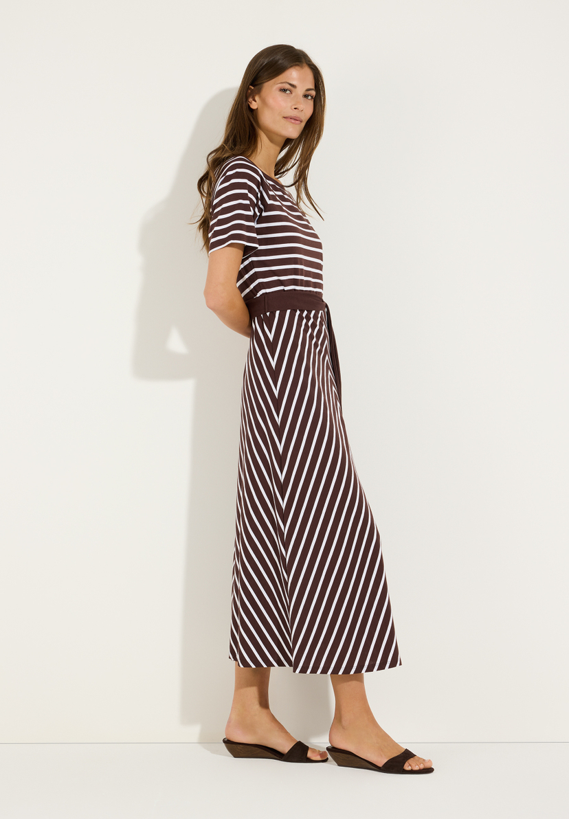 MORE & MORE Jersey-Kleid gestreift. Modell trägt ein braunes Kleid mit weißen Querstreifen oben und diagonalen Streifen unten, dazu braune Sandalen. MORE & MORE Jersey-Kleid gestreift. Modell trägt ein braunes Kleid mit weißen Querstreifen oben und diagonalen Streifen unten, dazu braune Sandalen.