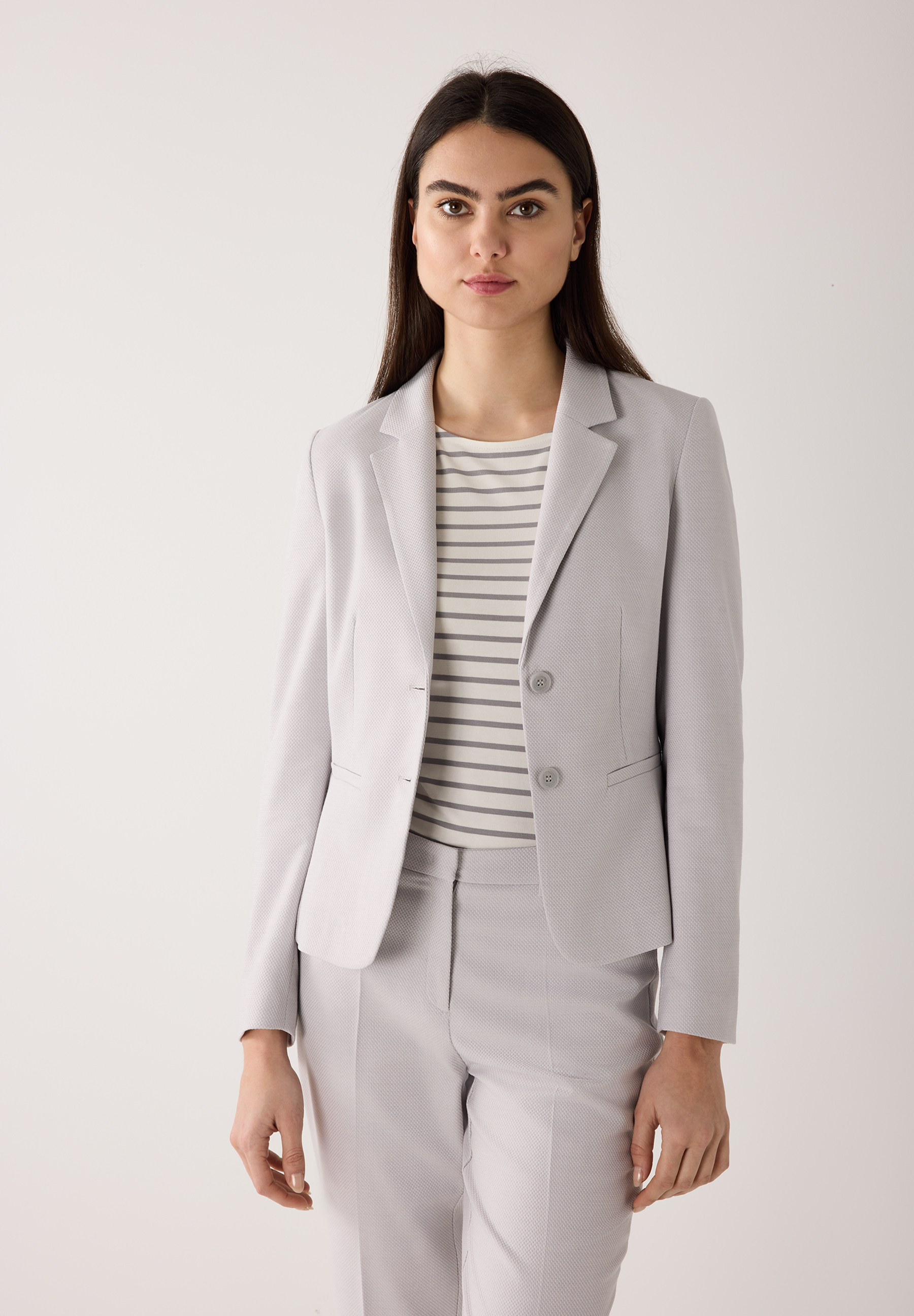 Eine Frau im MORE & MORE Blazer aus Piqué-Stretch vor neutralem Hintergrund. Eine Frau im MORE & MORE Blazer aus Piqué-Stretch vor neutralem Hintergrund.