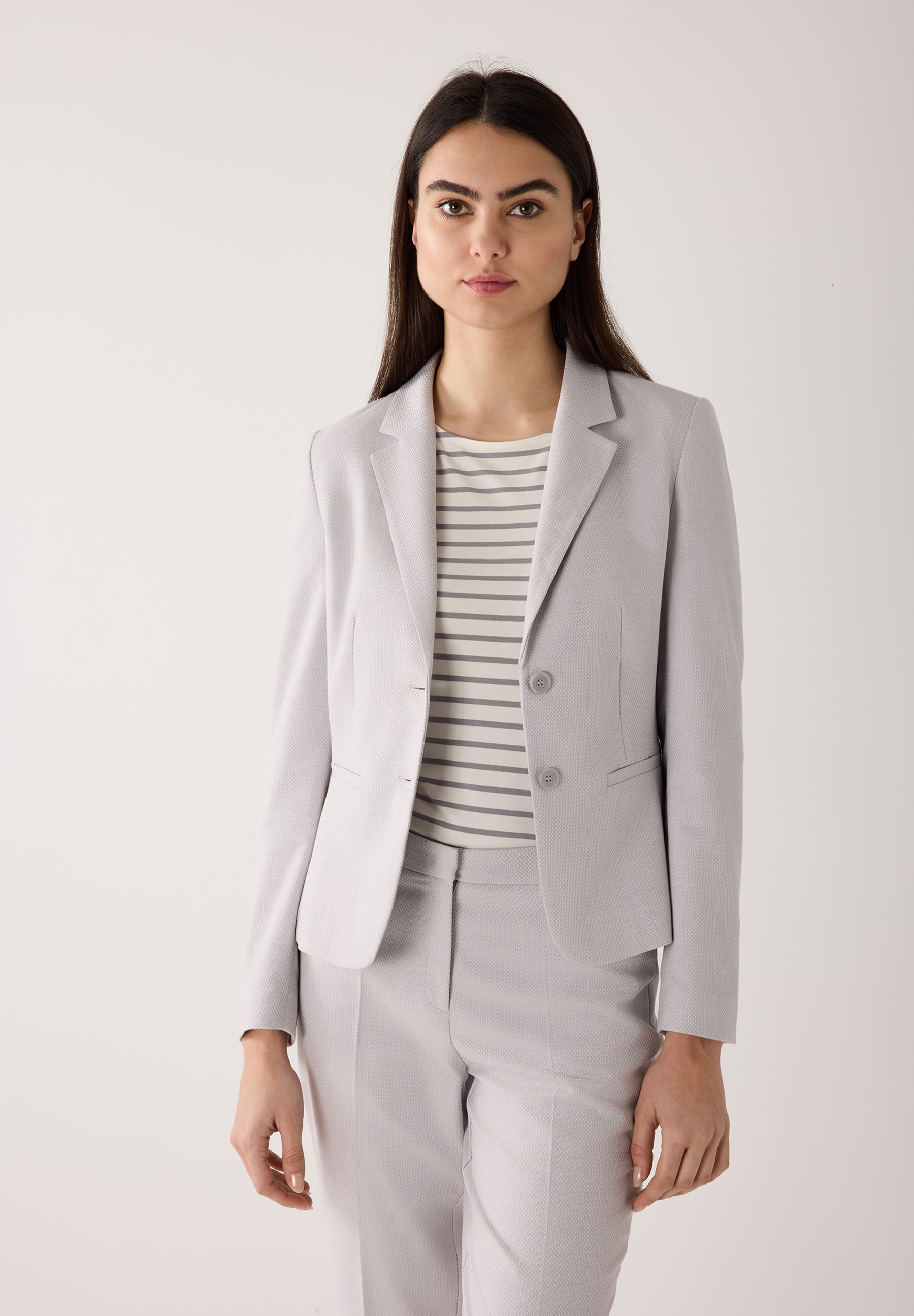 Eine Frau im MORE & MORE Blazer aus Piqué-Stretch vor neutralem Hintergrund.