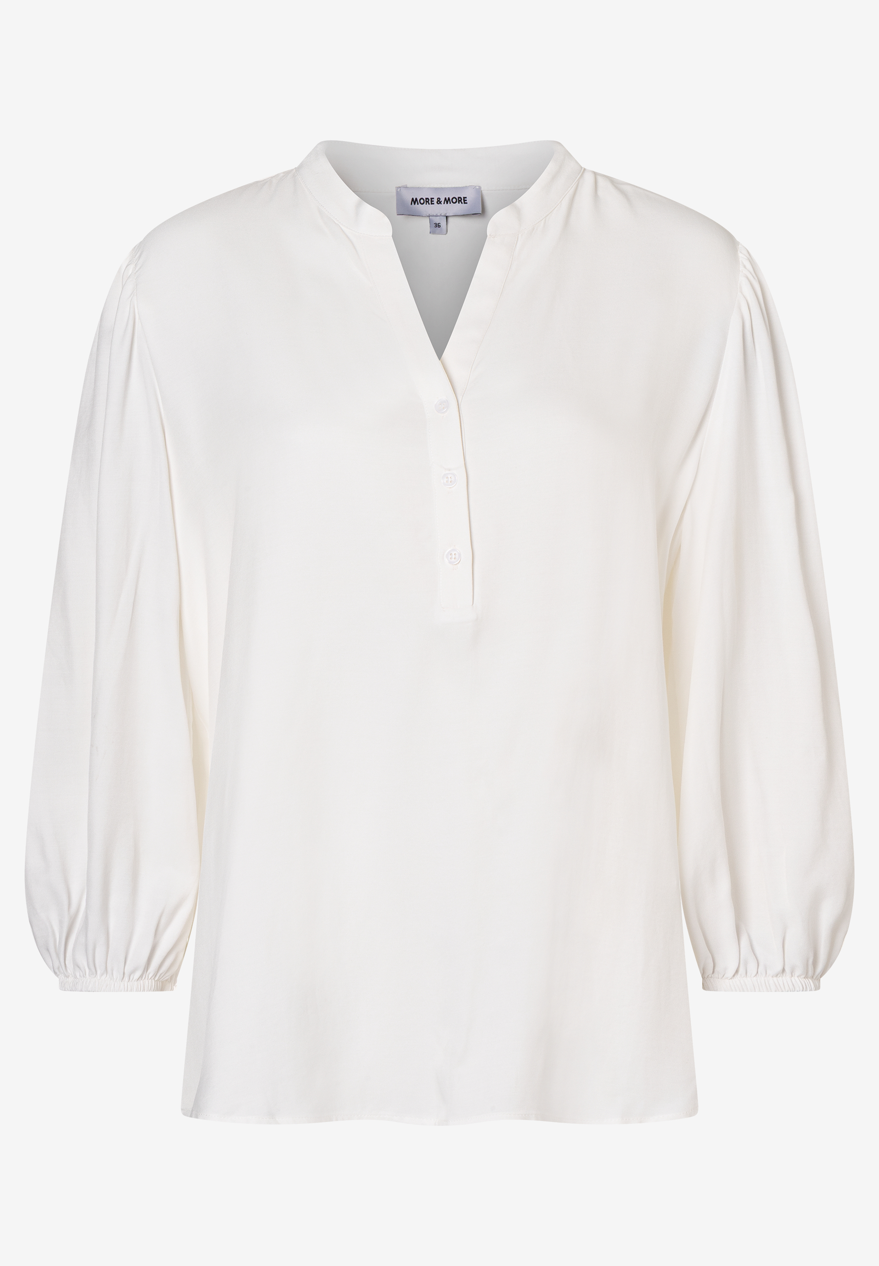 Eine weiße Bluse von MORE & MORE mit V-Ausschnitt und Knopfleiste, langen Ärmeln und fließendem Viskosematerial. Eine weiße Bluse von MORE & MORE mit V-Ausschnitt und Knopfleiste, langen Ärmeln und fließendem Viskosematerial.