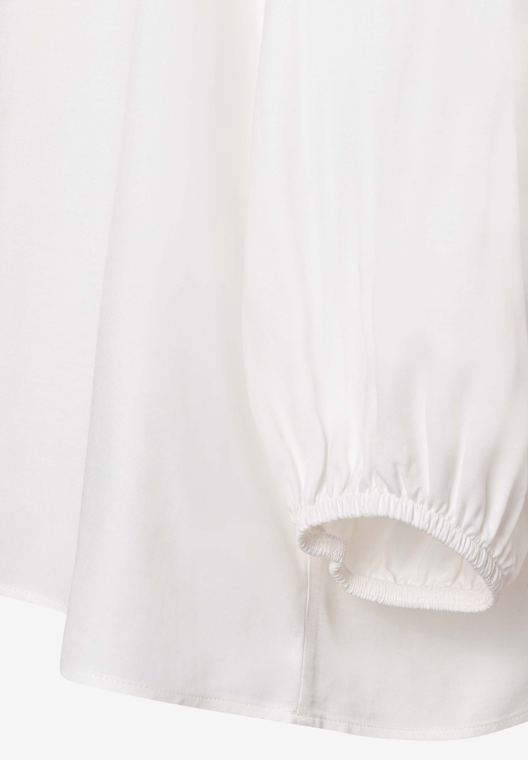 Detailaufnahme einer weißen MORE & MORE Bluse mit fließender Viskose-Konstruktion und gerafftem Ärmel. Detailaufnahme einer weißen MORE & MORE Bluse mit fließender Viskose-Konstruktion und gerafftem Ärmel.