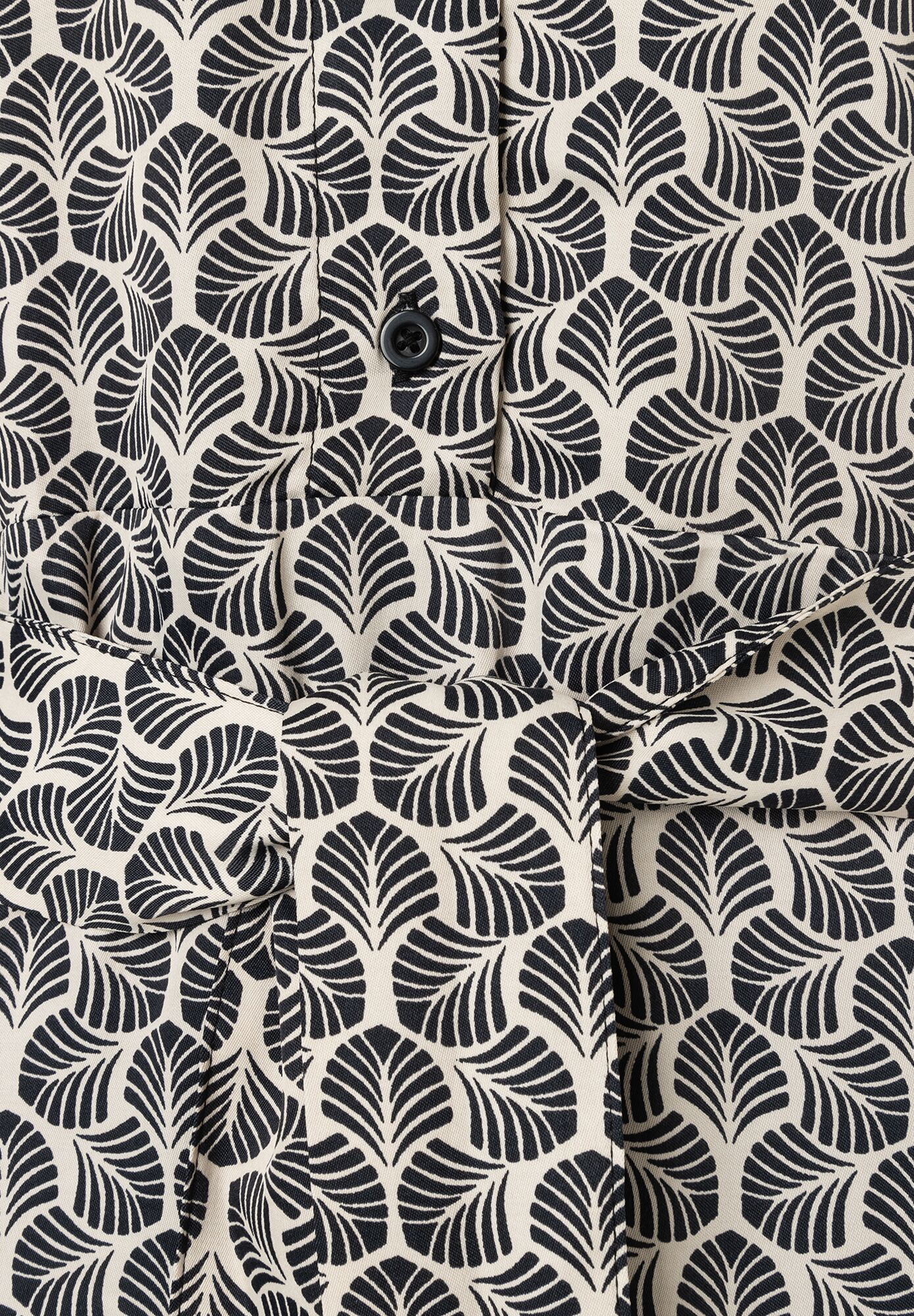 Detailaufnahme eines MORE & MORE Oberteils mit Blattmuster und Knopf. Detailaufnahme eines MORE & MORE Oberteils mit Blattmuster und Knopf.