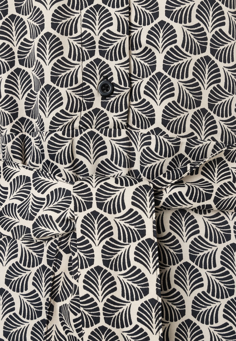 Detailaufnahme eines MORE & MORE Oberteils mit Blattmuster und Knopf. Detailaufnahme eines MORE & MORE Oberteils mit Blattmuster und Knopf.